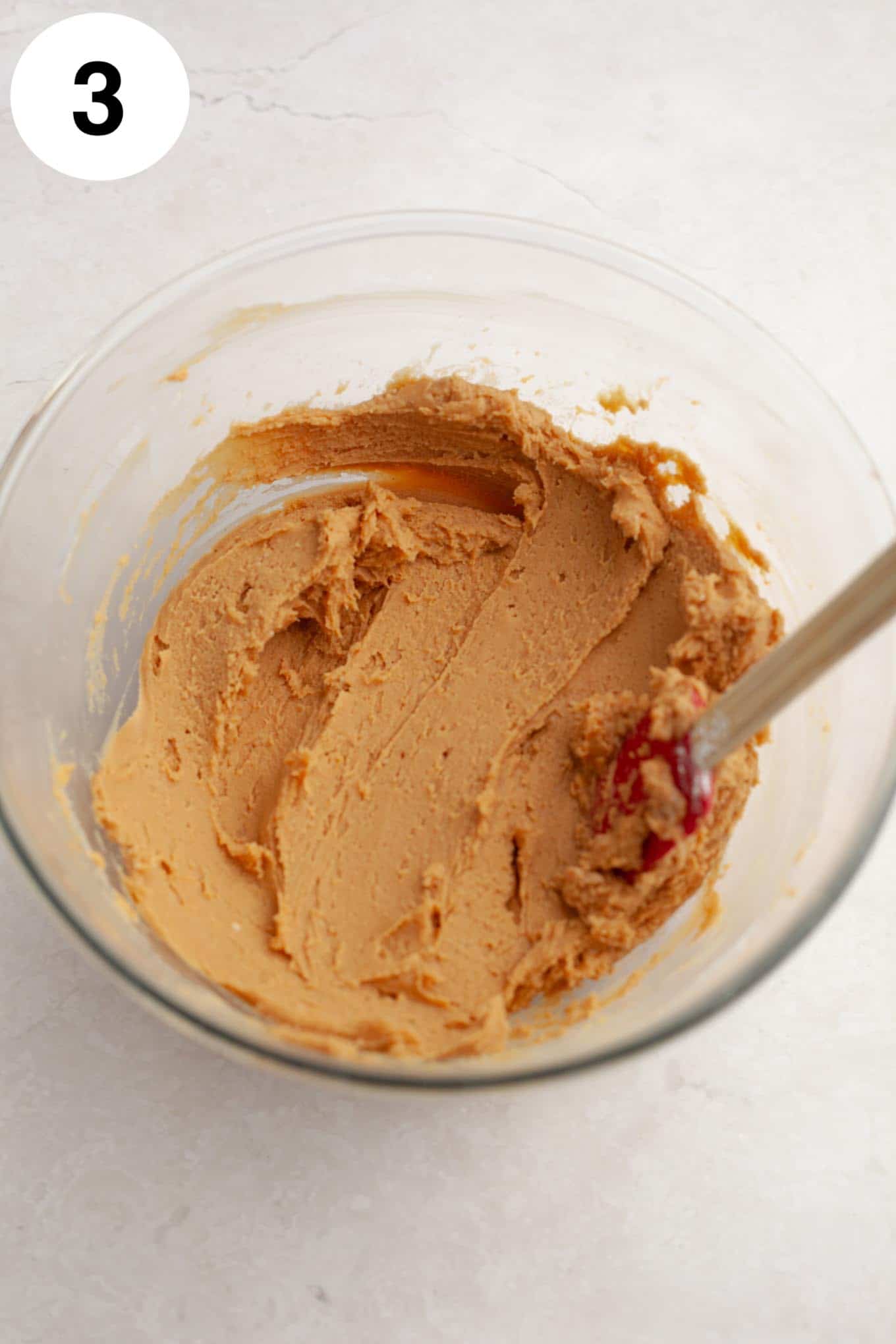 An overhead view of peanut butter fudge in a glass mixing bowl. 