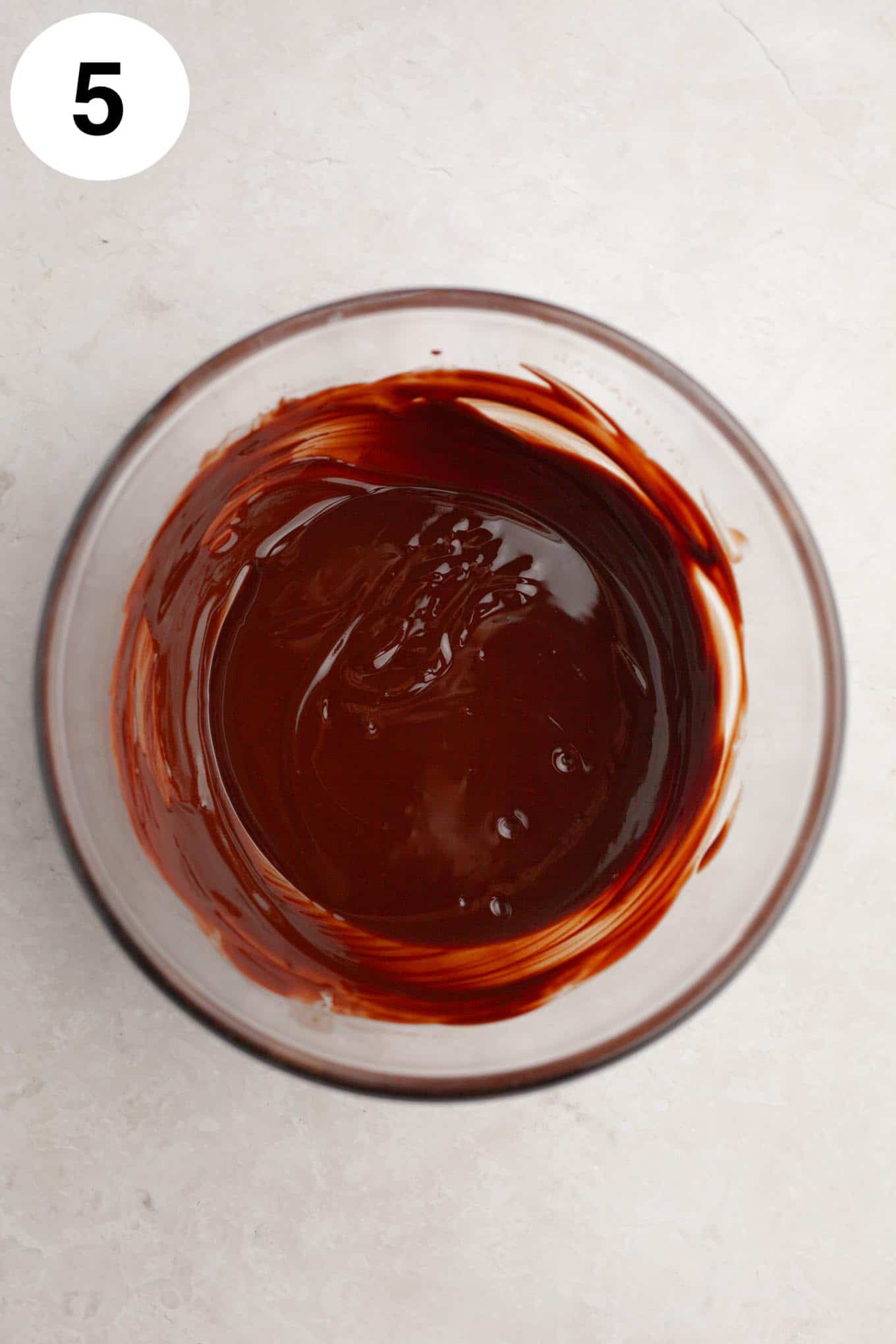 An overhead view of melted chocolate in a glass bowl. 