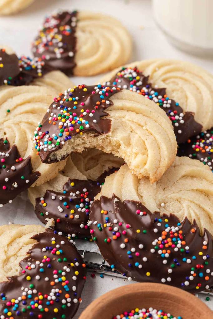 Simple butter cookies piled on top of each other. The top cookie has a bite missing. 