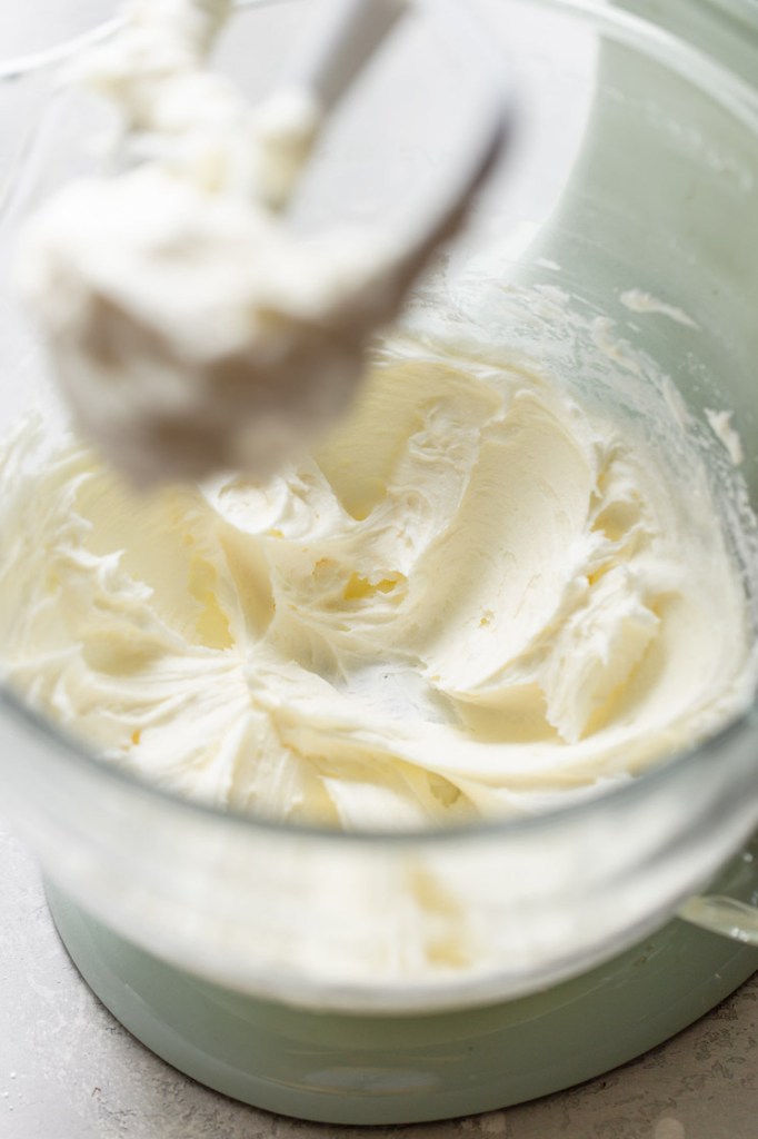 A glass mixing bowl filled with butter that has been mixed until it's smooth.