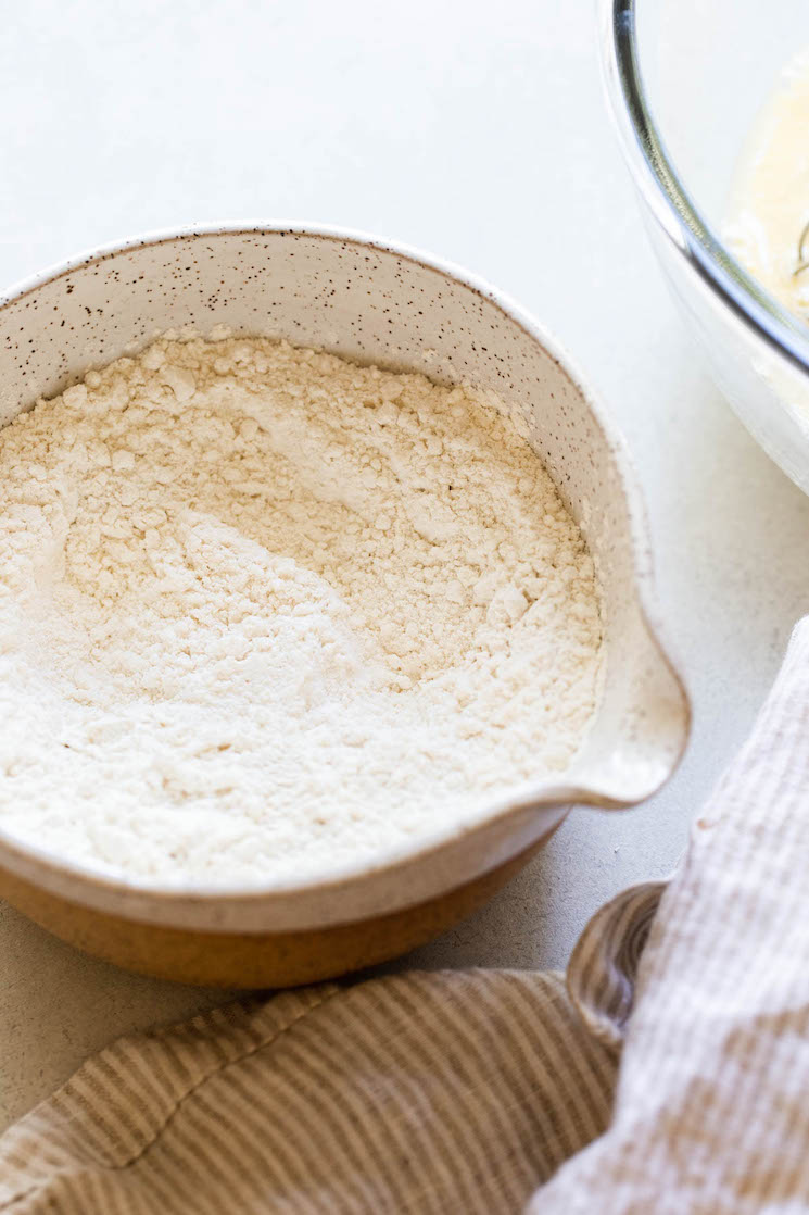 The dry ingredients for buttermilk pancakes mixed together in a white speckled clay bowl.