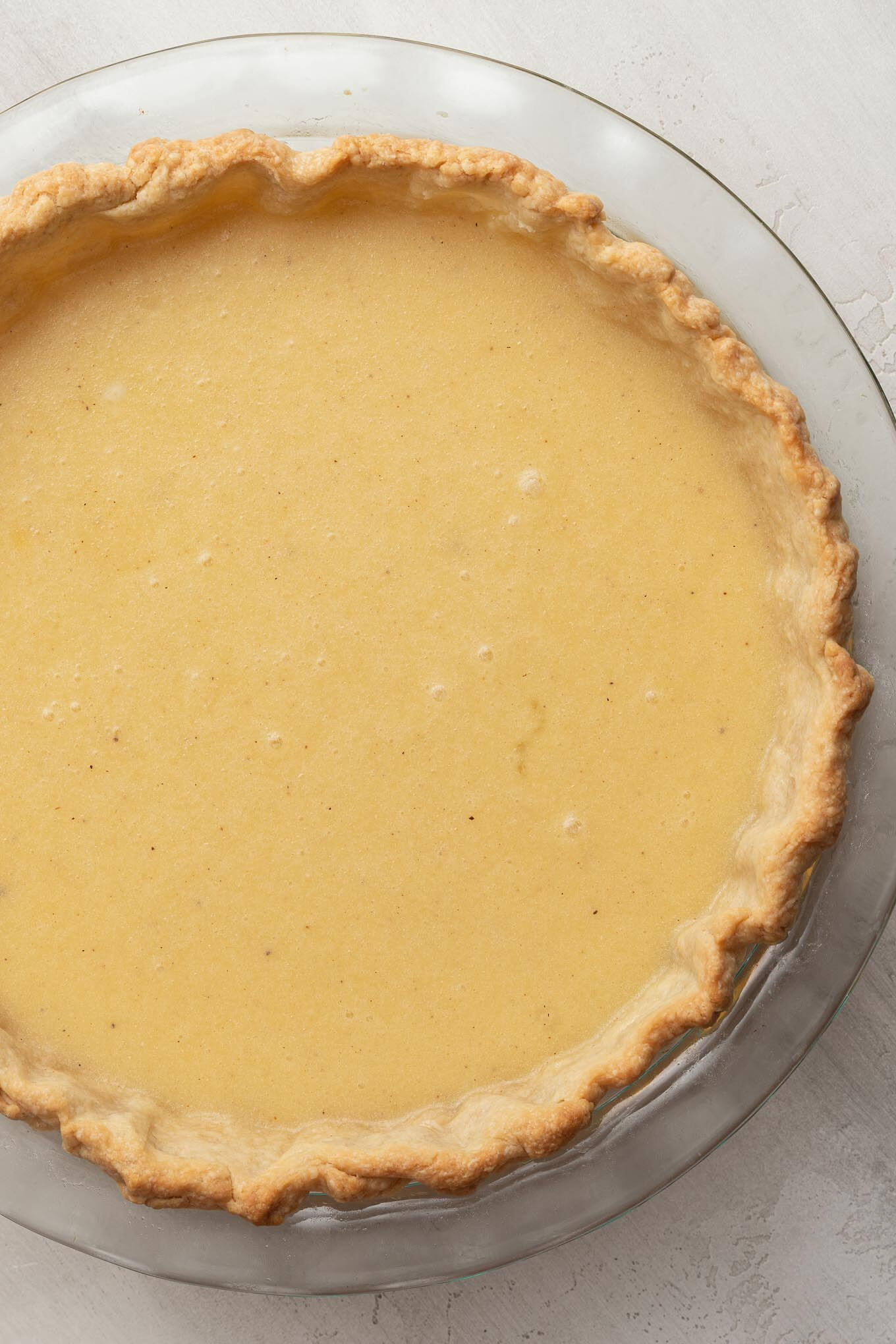 Unbaked buttermilk pie in a glass pie plate.