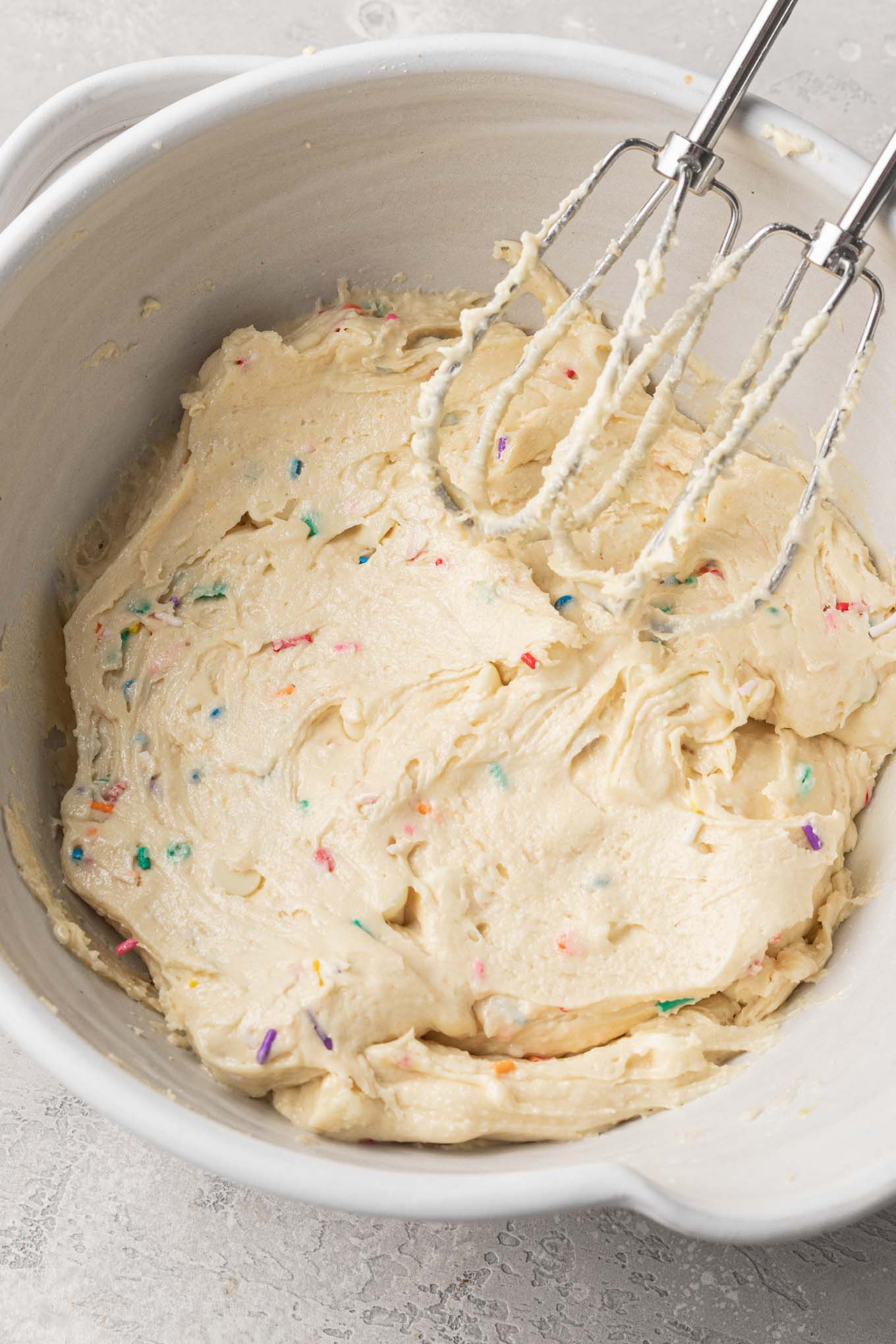 Cookie dough in a mixing bowl, with electric beaters resting on the side. 