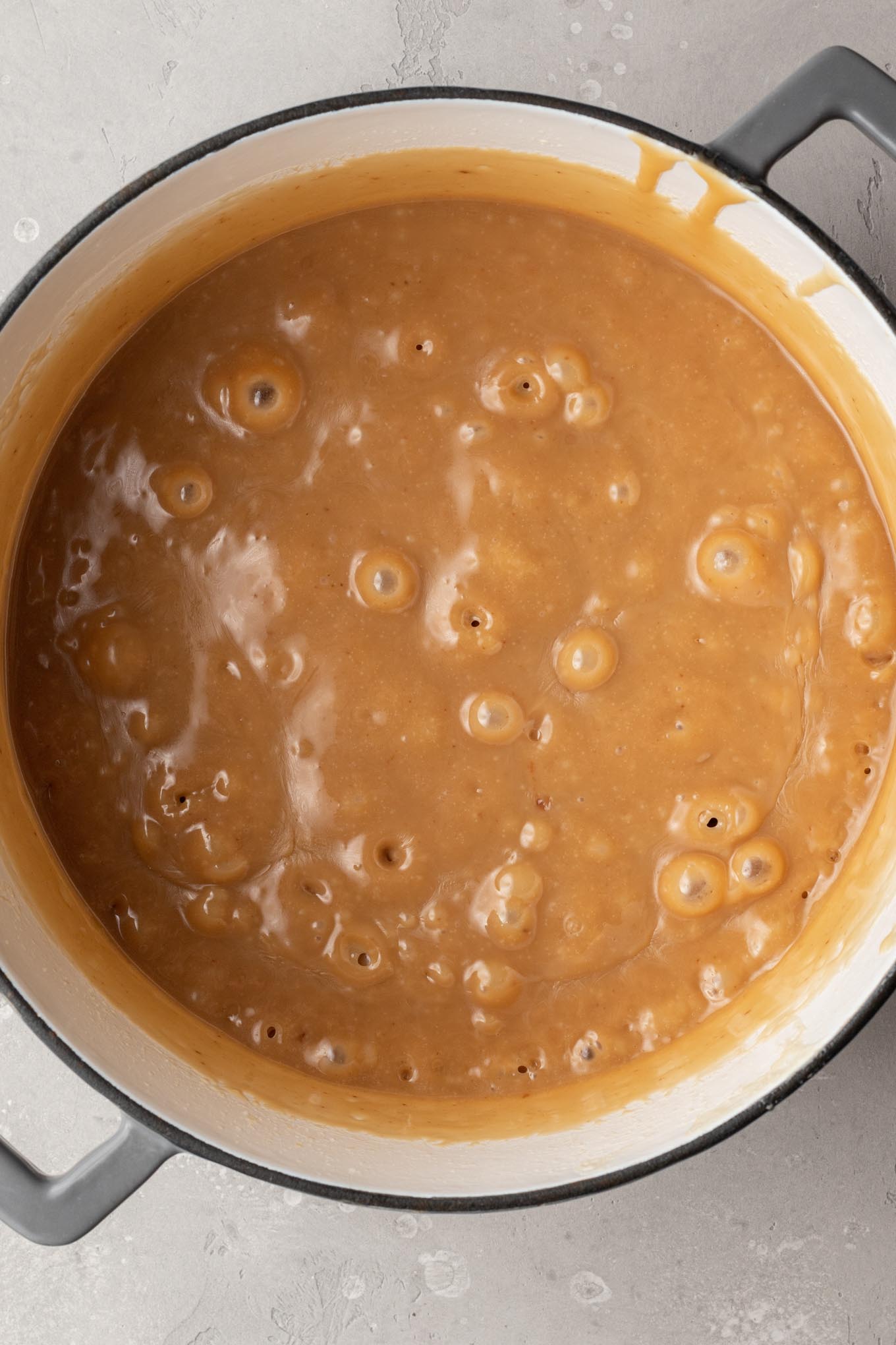 An overhead view of thickened, bubbling caramel in a saucepan.