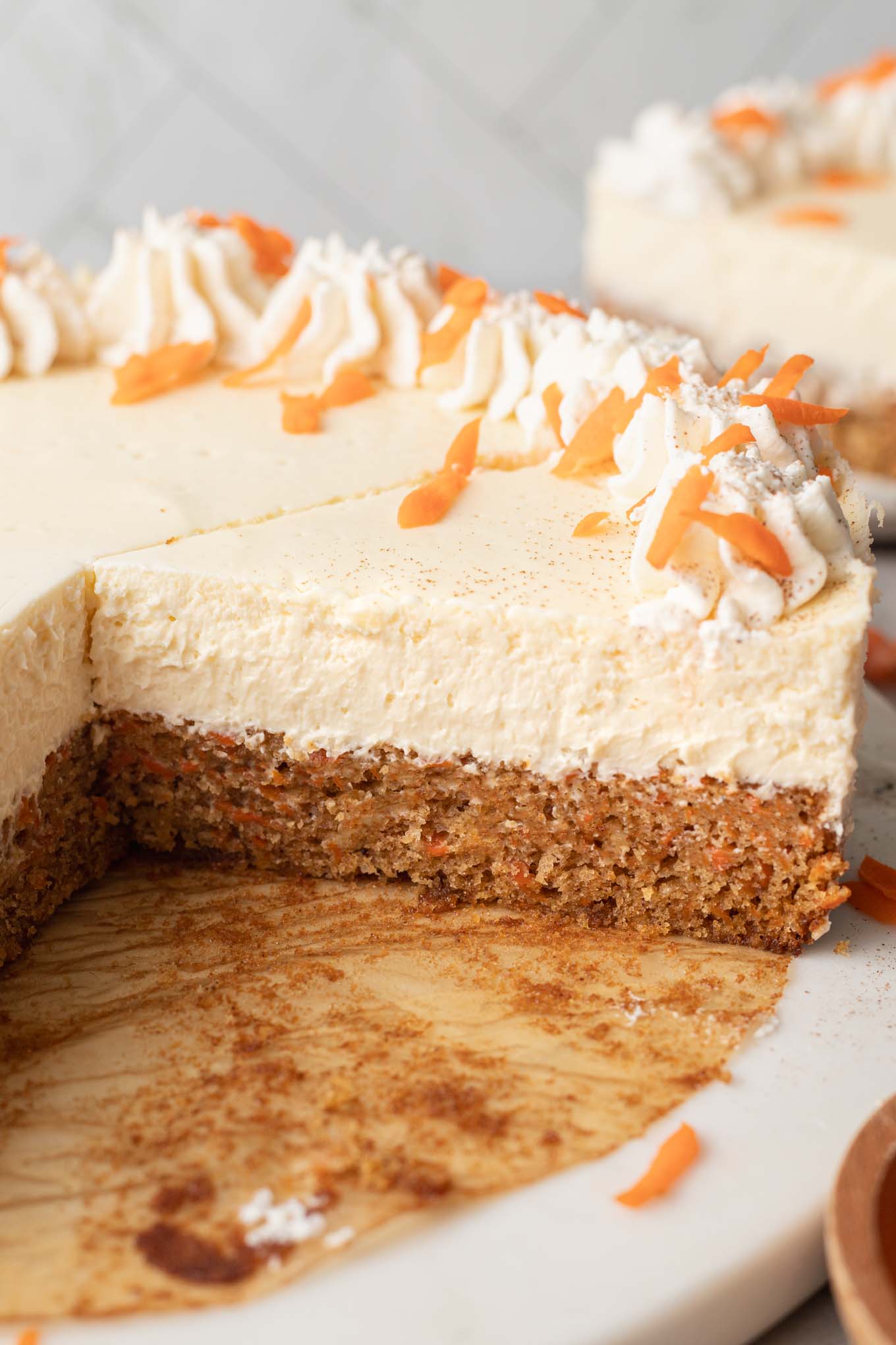 A side view of a sliced carrot cake cheesecake. 