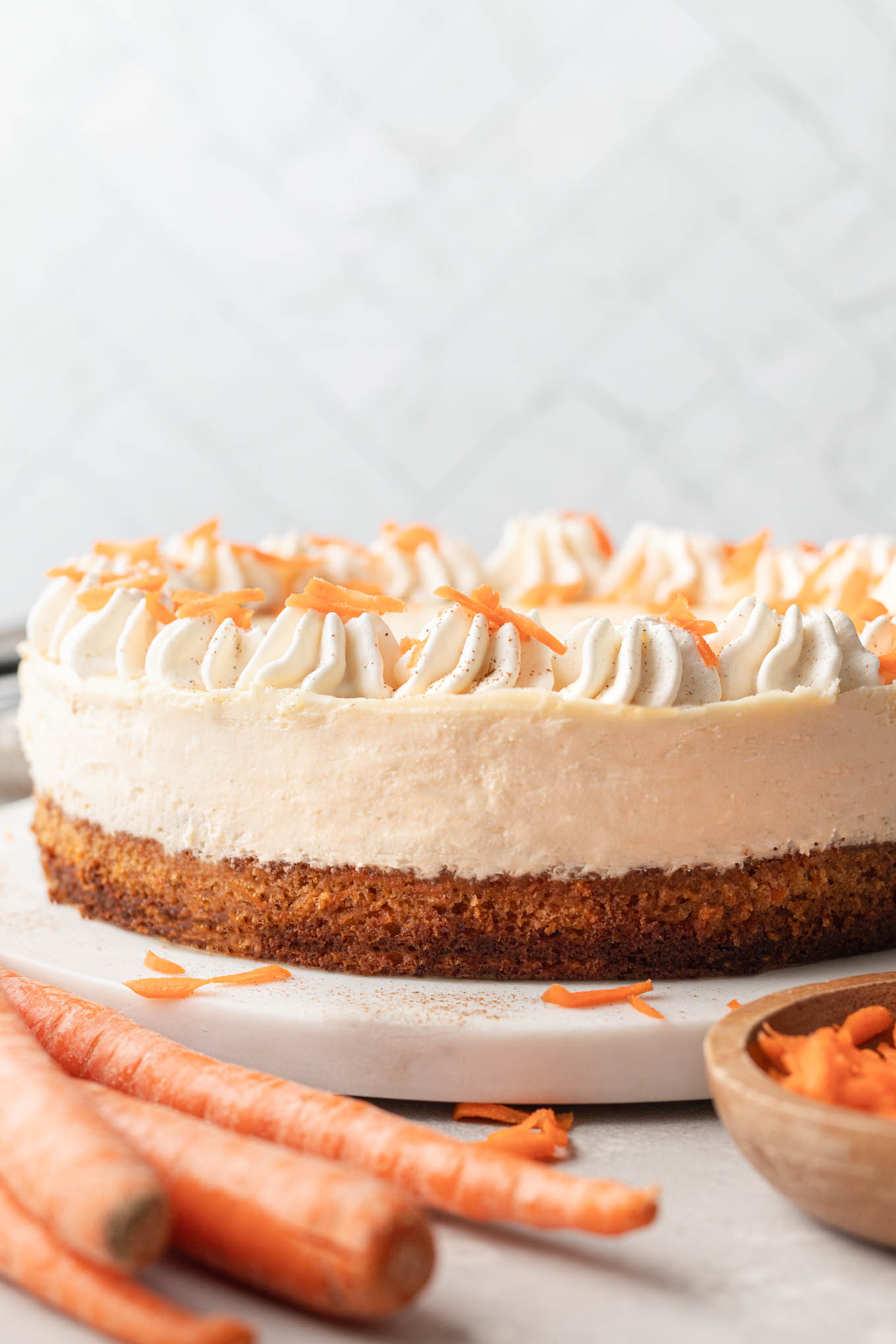 A side view of a layered carrot cake cheesecake. 