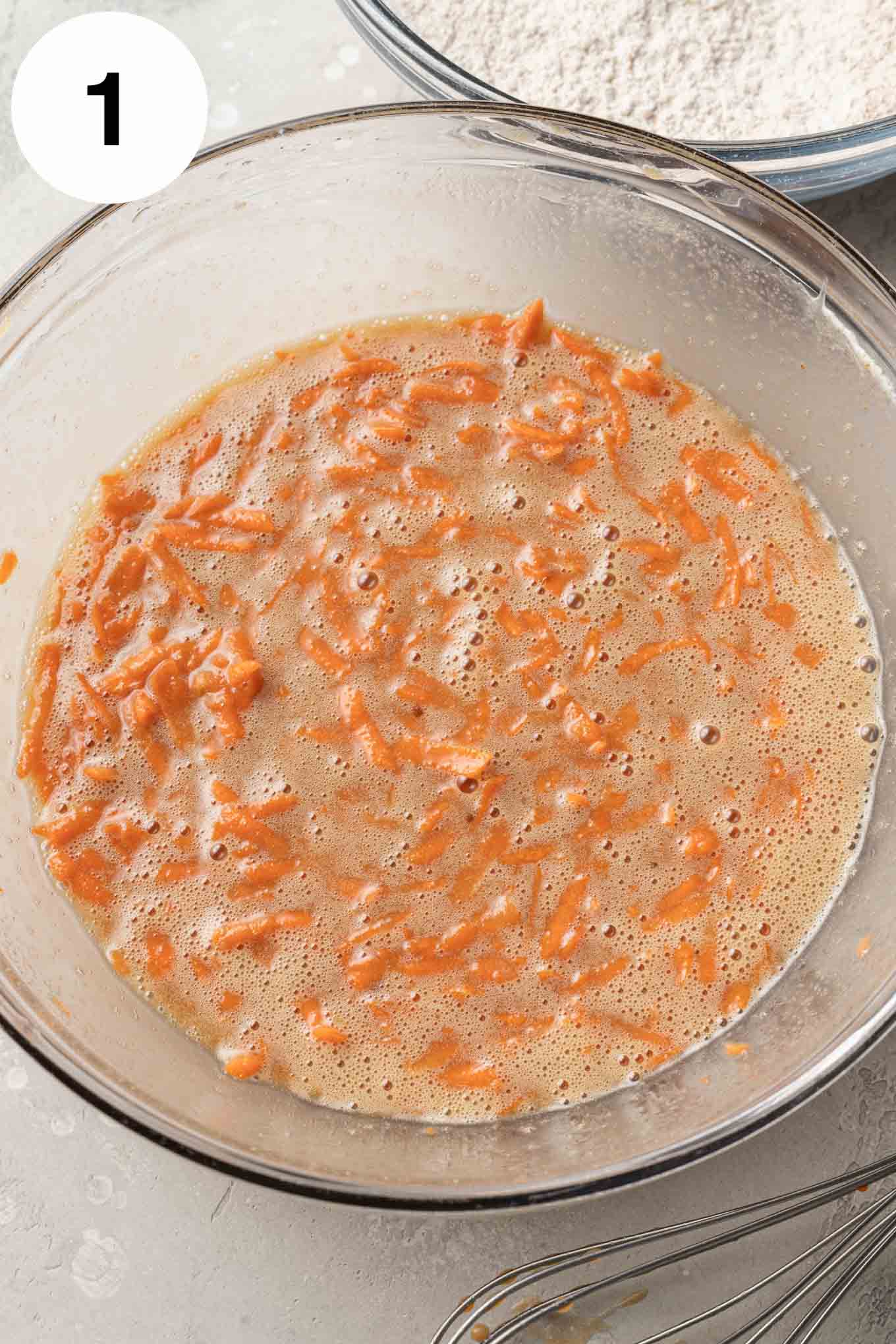 An overhead view of the wet ingredients in a glass mixing bowl. 