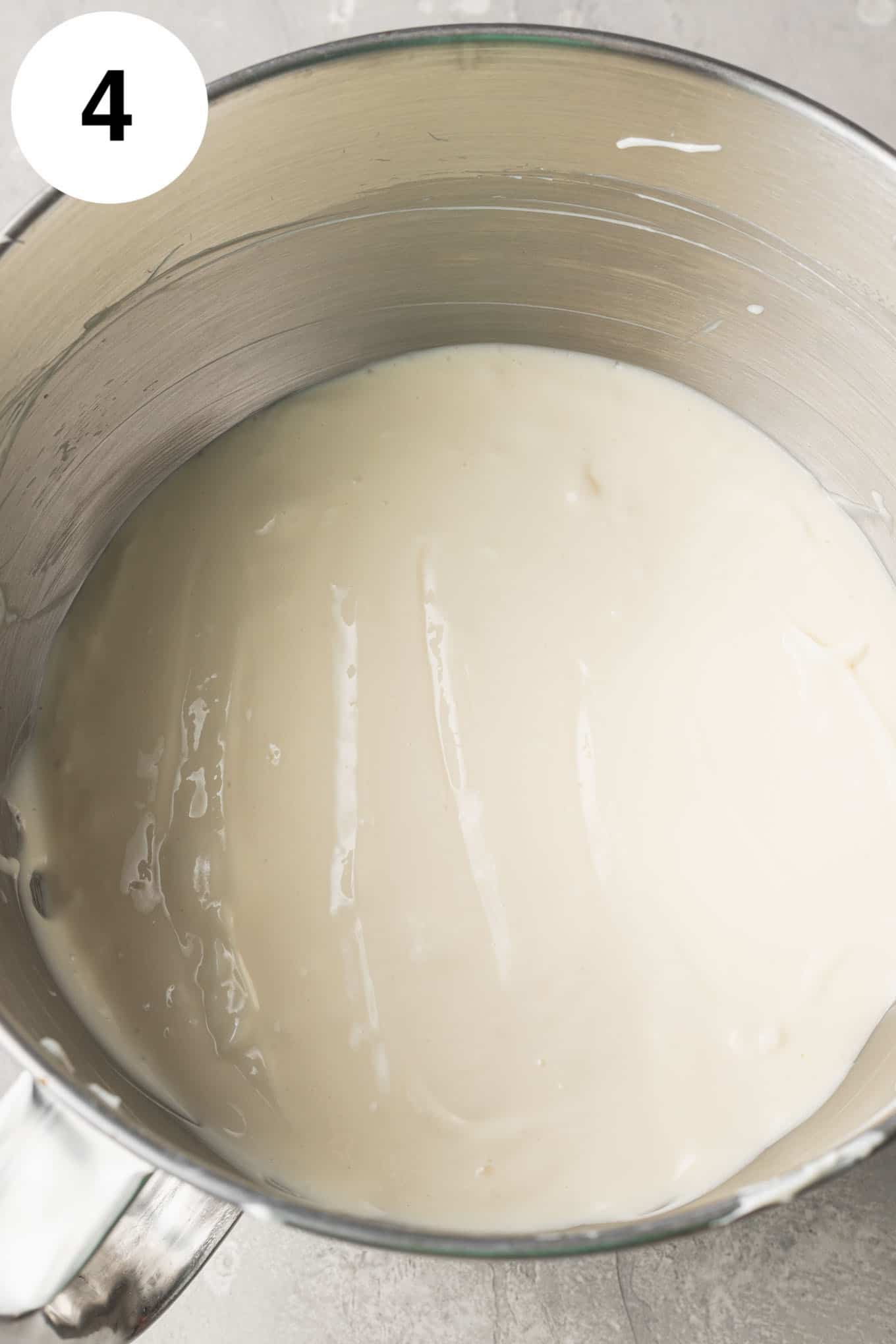 An overhead view of cheesecake filling in the bowl of a stand mixer. 