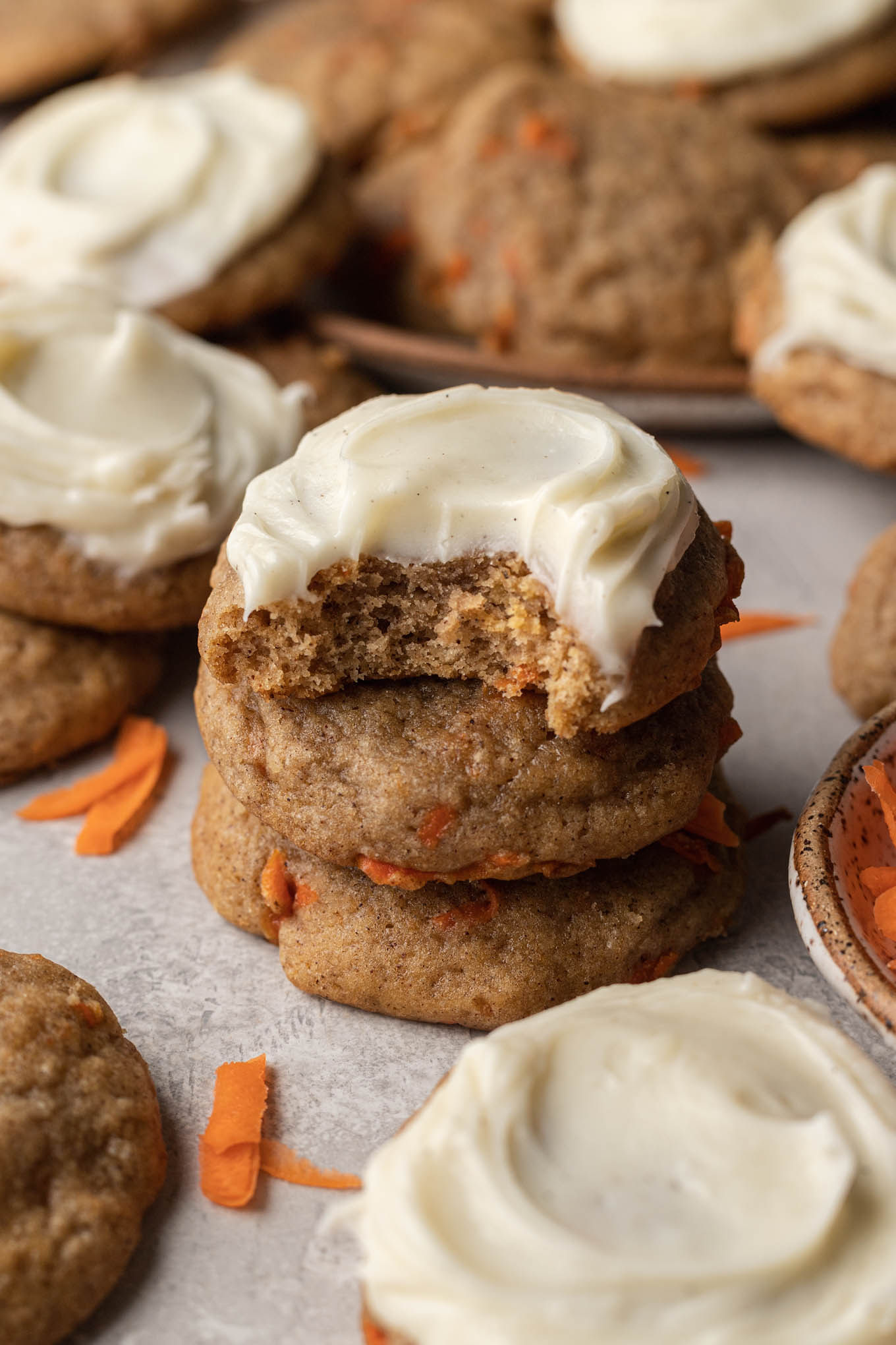 A stack of frosted carrot cake cookies, amongst other cookies. 