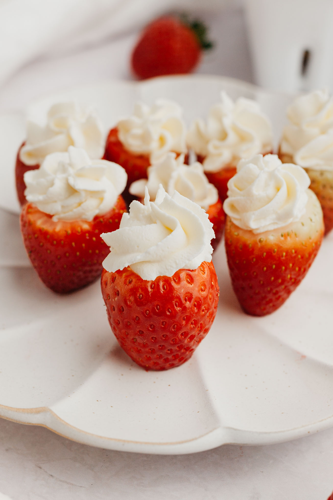 Several cheesecake stuffed strawberries standing up on a white plate.