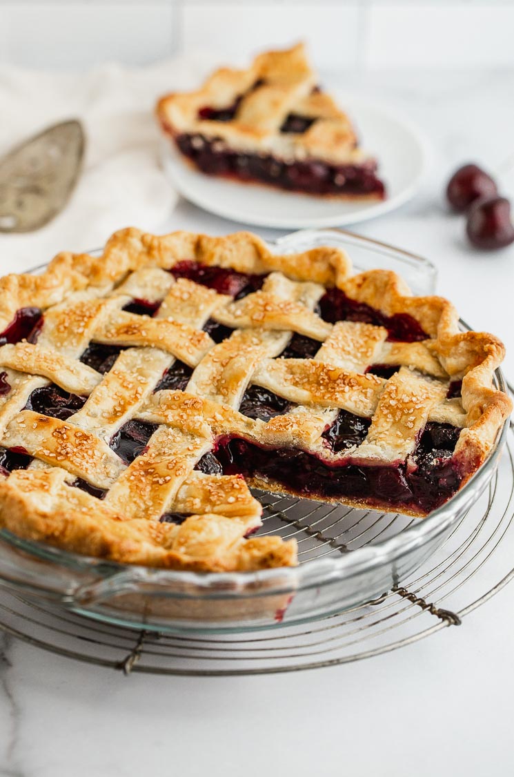 A cherry pie with one slice taken out showing the lattice crust and cherry filling. 