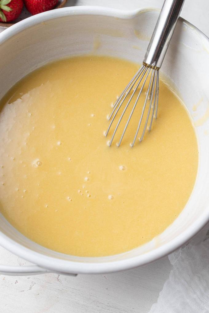 Egg yolk mixture in a mixing bowl with a whisk.