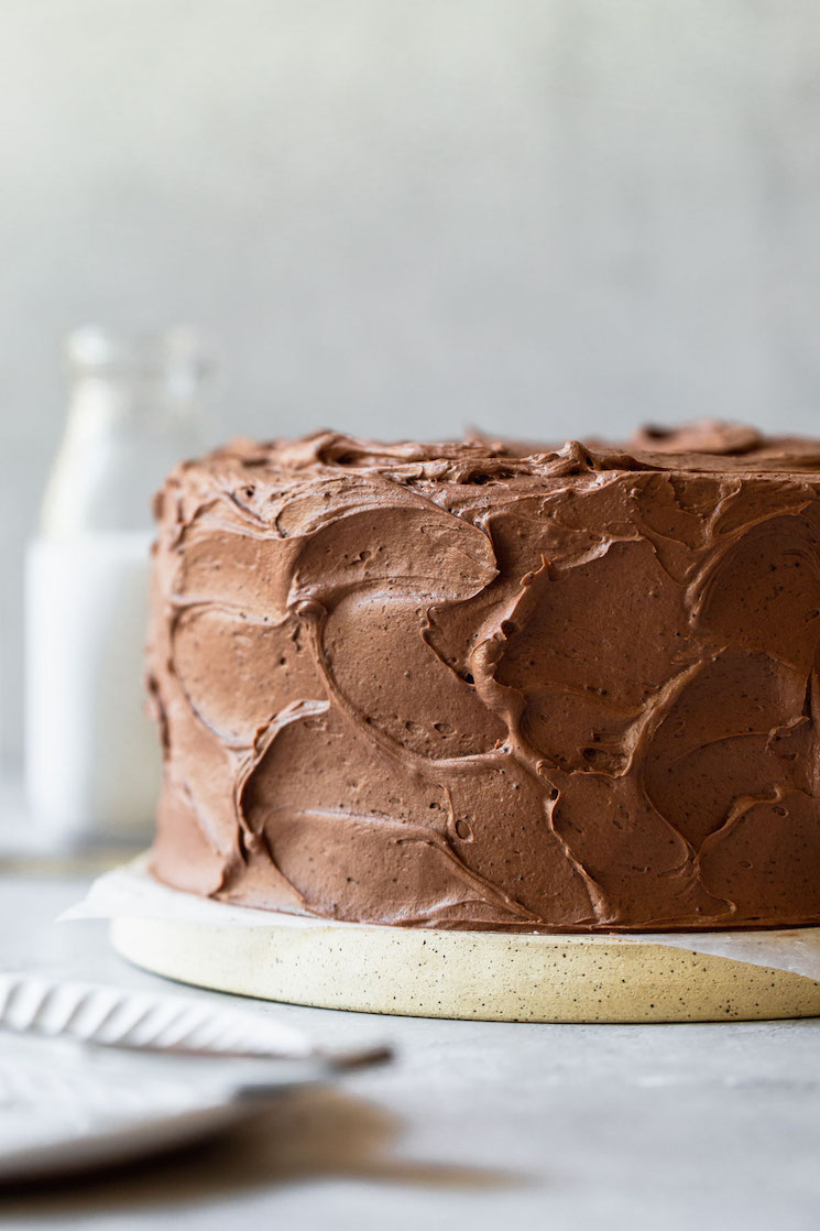 A chocolate cake decorated with chocolate icing on a cake stand. 