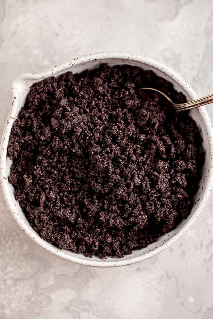 An overhead view of crushed Oreos in a large white mixing bowl.