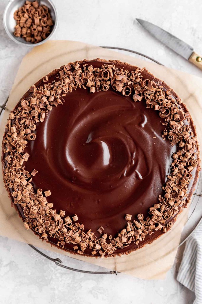 An overhead view of a chocolate cheesecake that's been garnished with chocolate ganache and chocolate shavings. 