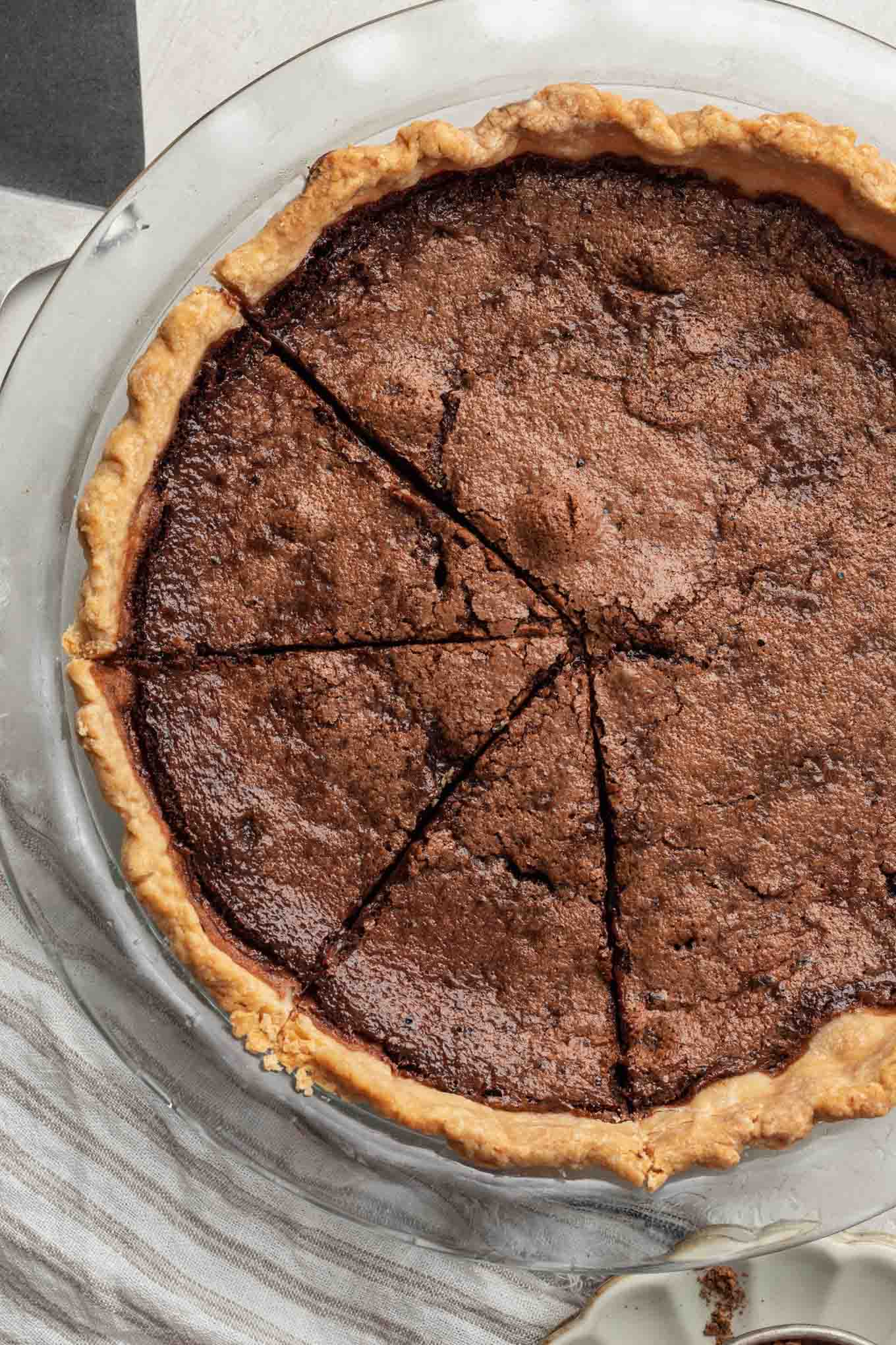 An overhead view of a chocolate chess pie. Three slices have been cut. 