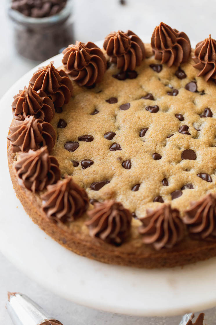 A finished cookie cake displayed on top of a marble cake stand.