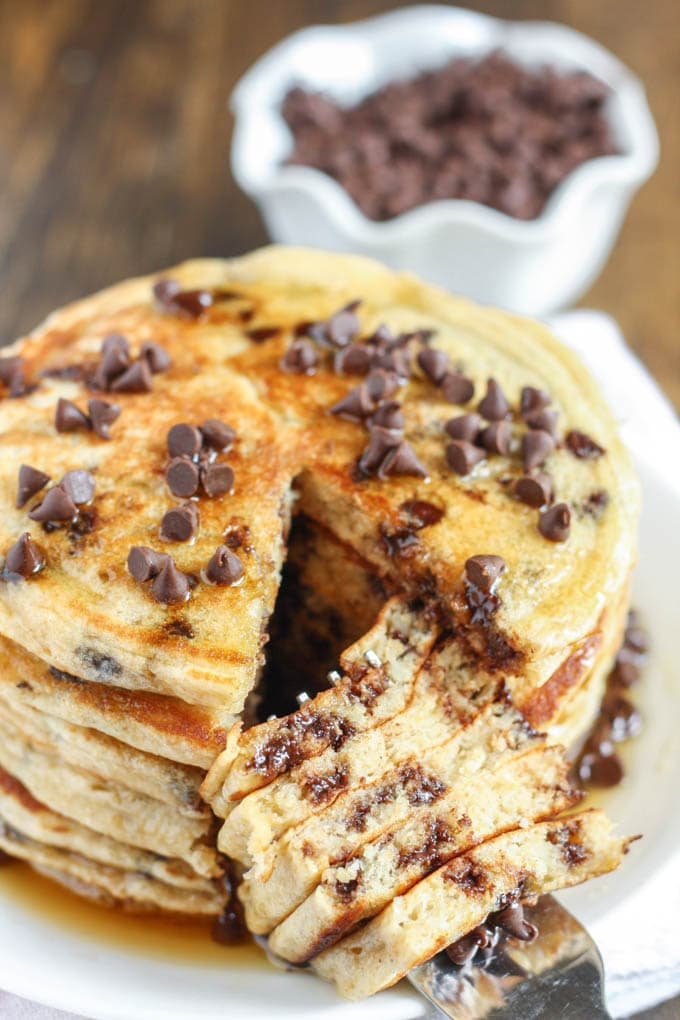 A stack of Chocolate Chip Greek Yogurt Pancakes. A bite has been cut out.