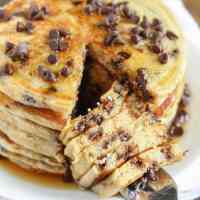 A stack of Chocolate Chip Greek Yogurt Pancakes. A bite has been cut out.