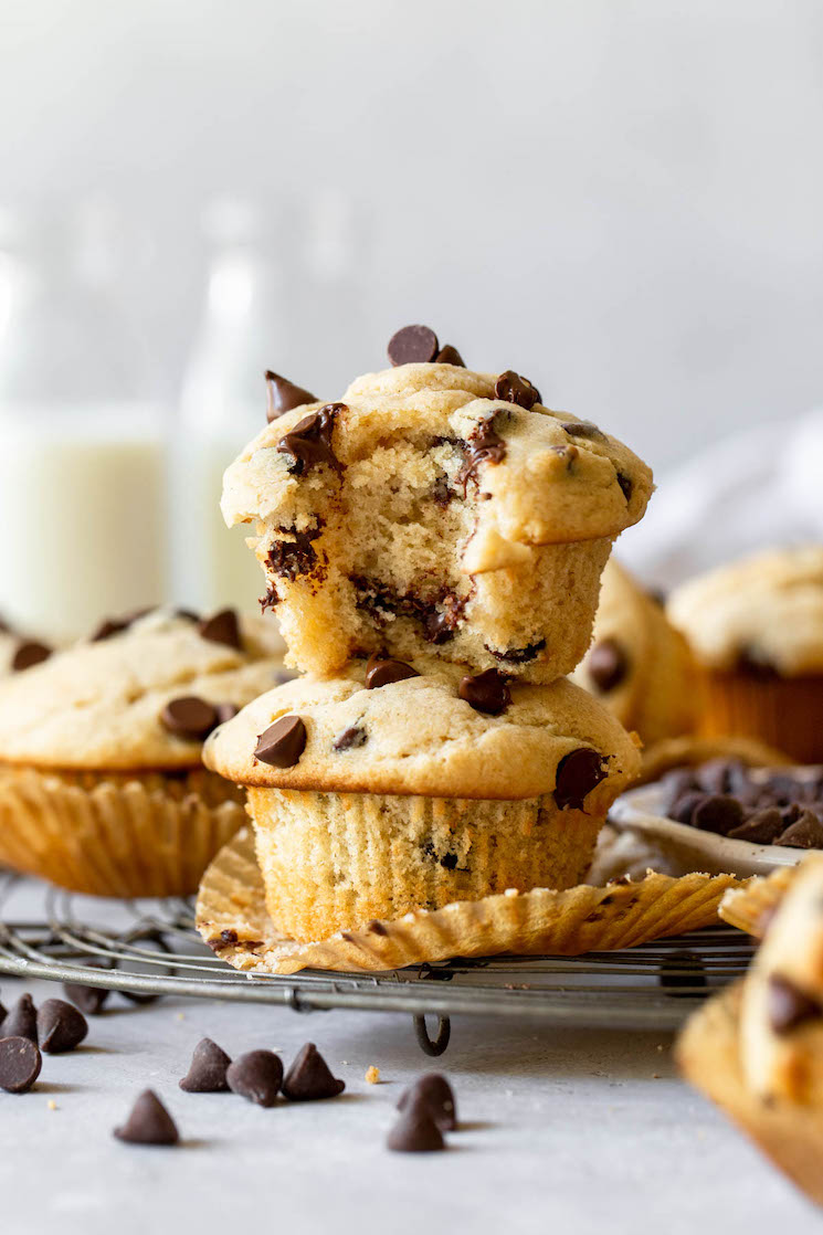 Two muffins stacked on top of each other with one having a bite taken out to show the texture of the muffin.