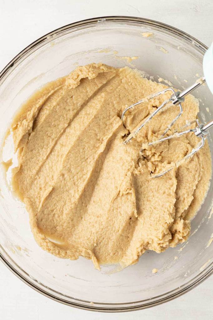 An overhead view of cookie dough in a glass mixing bowl.