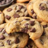 Several chocolate chip pudding cookies stacked on top of each other. The top cookie has a bite missing.