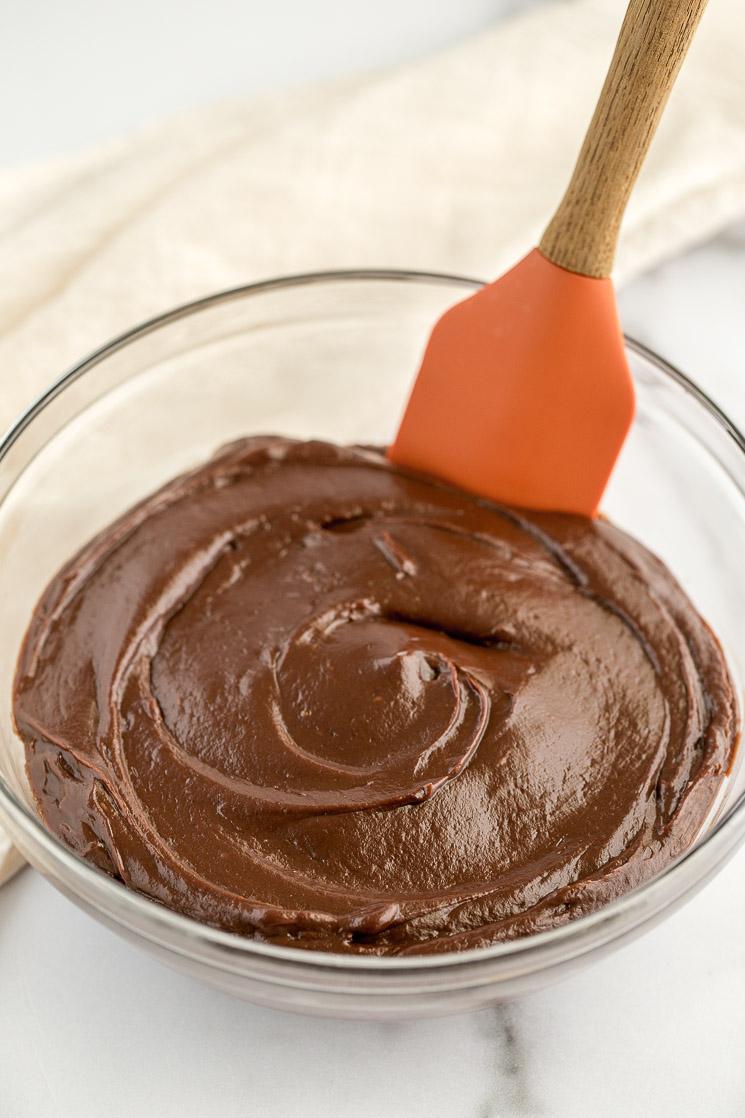 The chocolate filling inside of a glass bowl with a rubber spatula on the side.