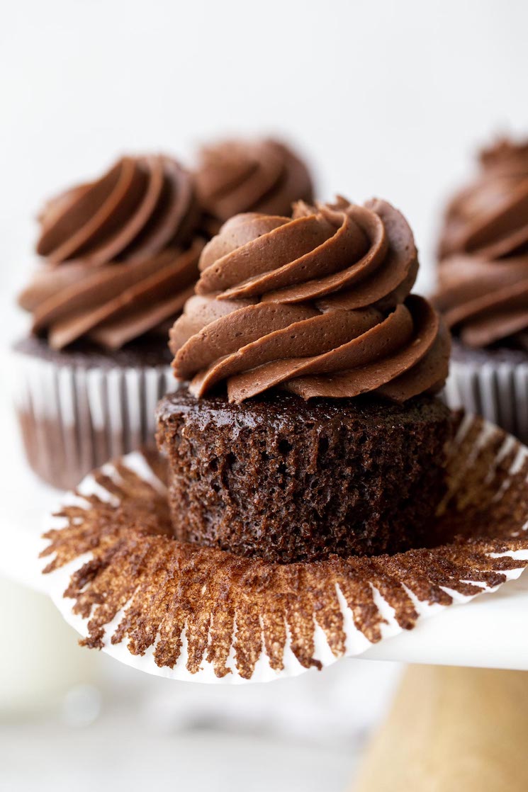 A marble cake stand holding chocolate cupcakes topped with chocolate frosting.