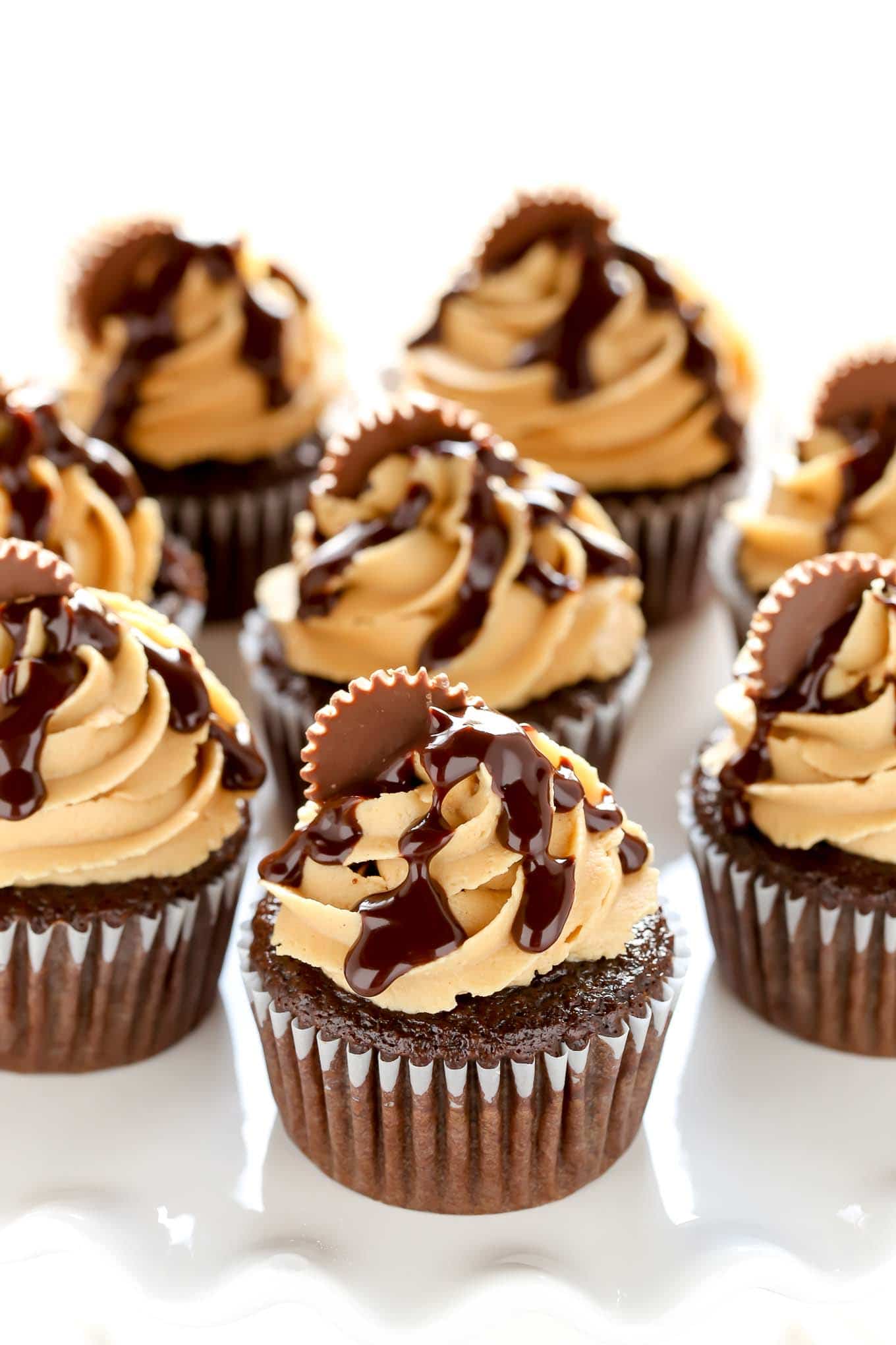 Chocolate cupcakes with peanut butter frosting on a white cake stand. 