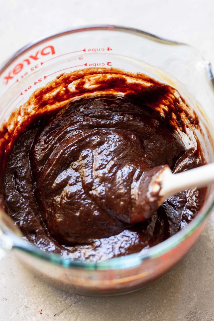 A glass mixing bowl with the egg and chocolate mixture being combined.