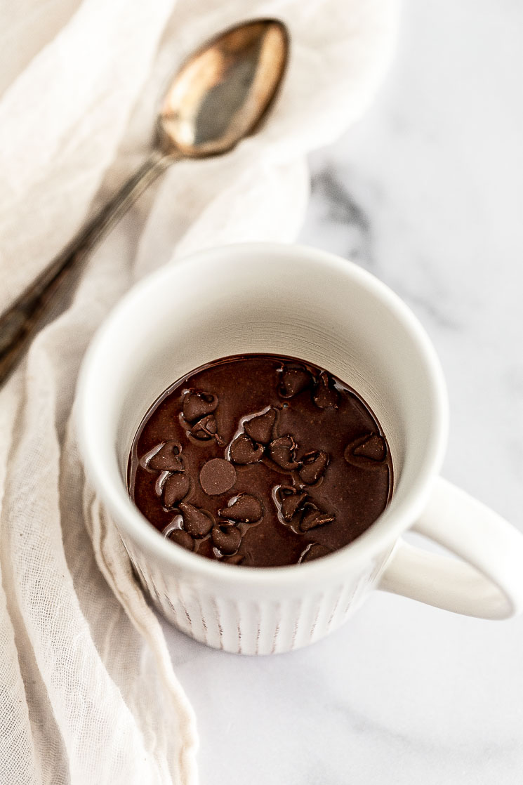 A white mug filled with mug cake batter ready to be put in the microwave.