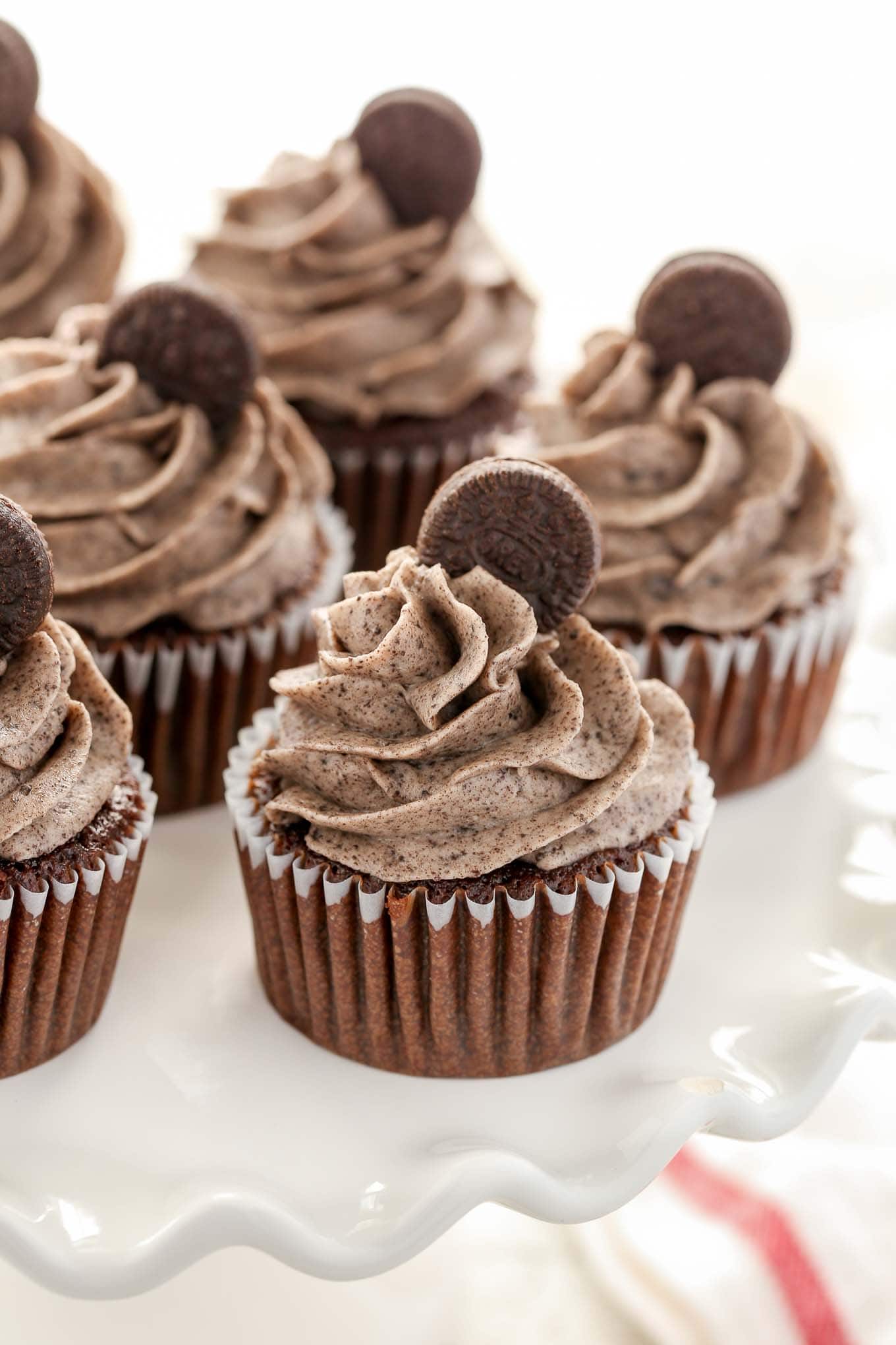 Chocolate Oreo cupcakes on a white cake stand. 