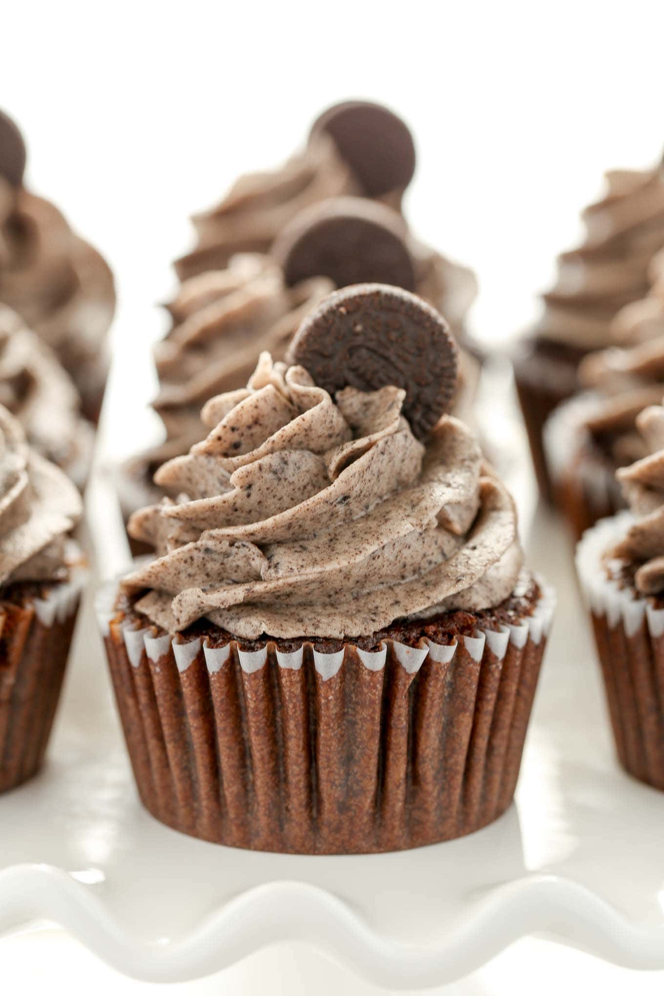 Three rows of Oreo cupcakes on a white cake stand. 