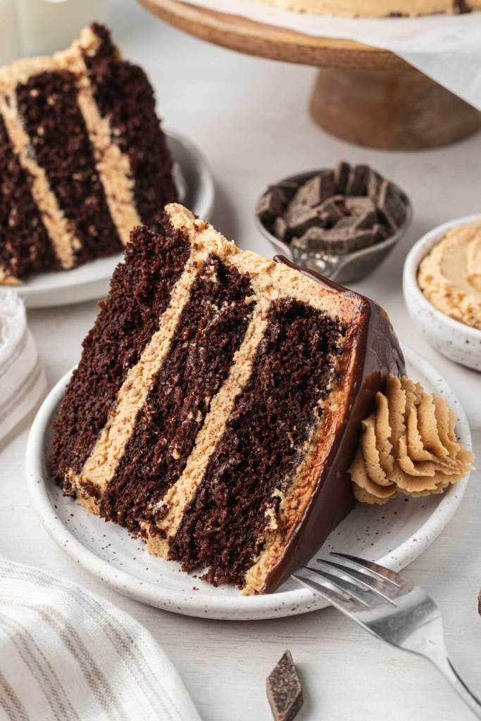 Two slices of chocolate peanut butter cake on white dessert plates. 