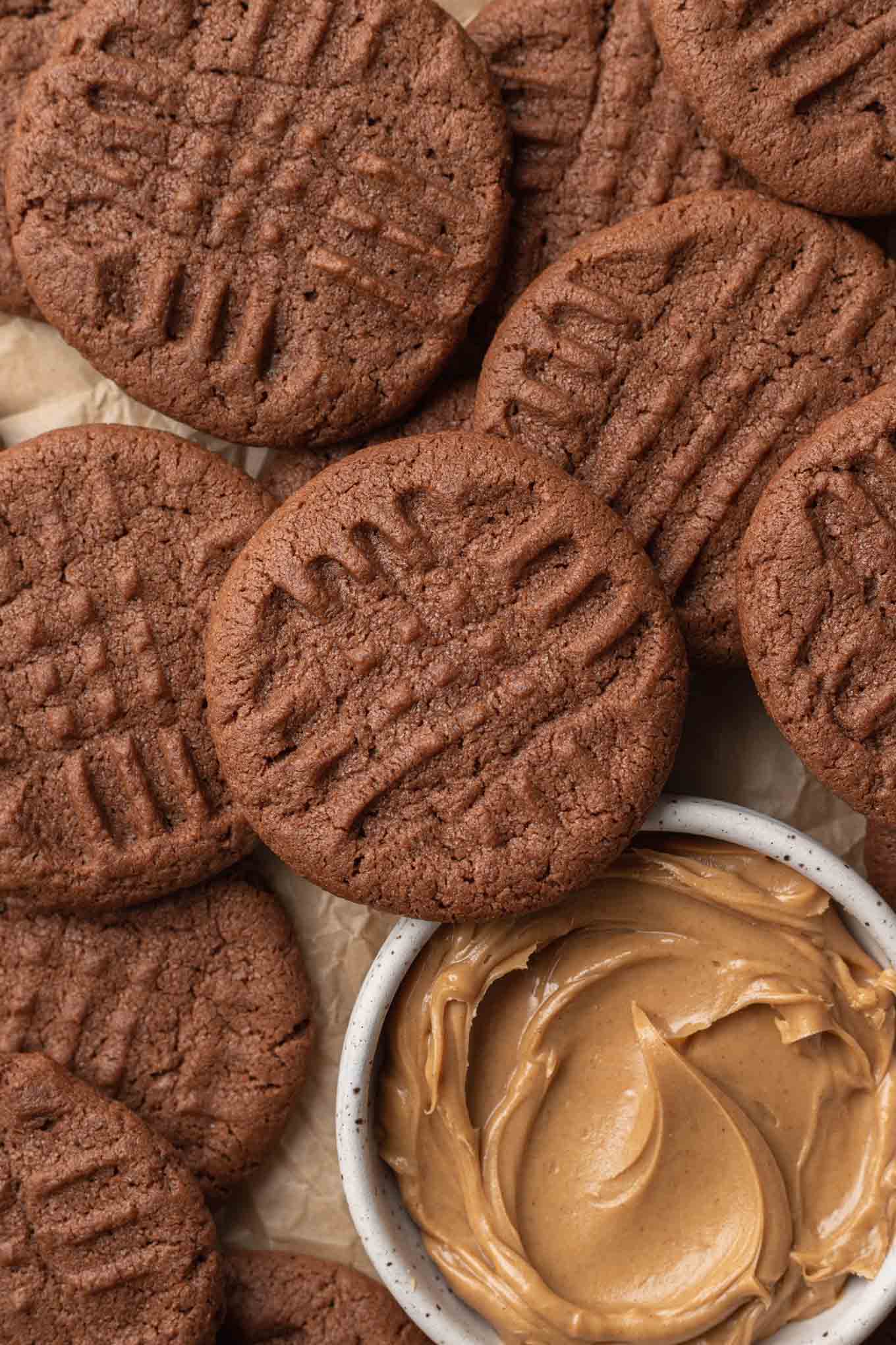 A close-up overhead view of chocolate and peanut butter cookies, with a dish of peanut butter. 