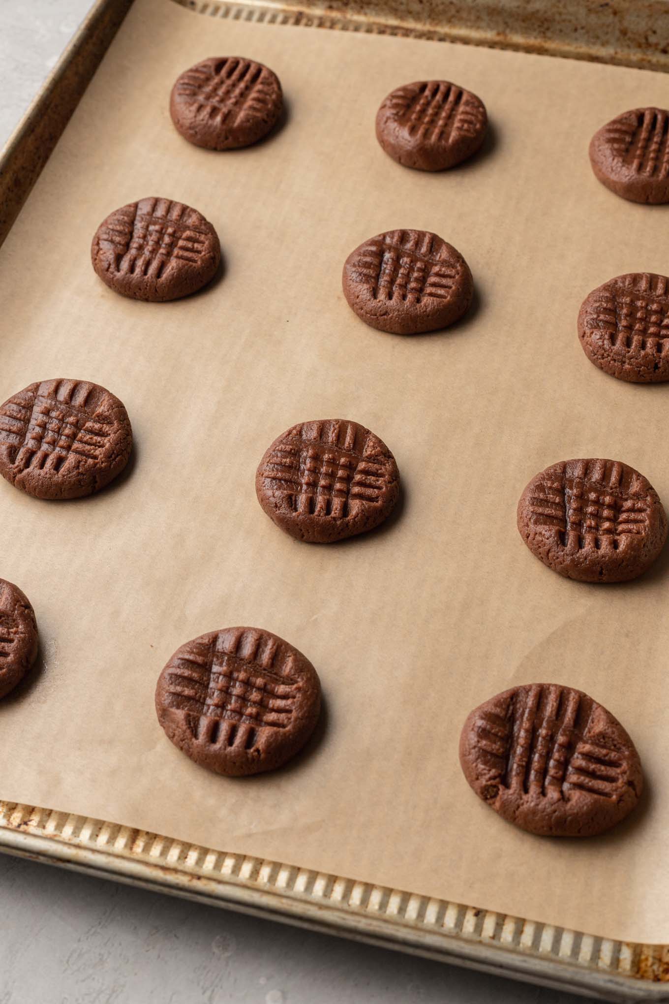 Unbaked chocolate and peanut butter cookie dough balls on a cookie sheet. 