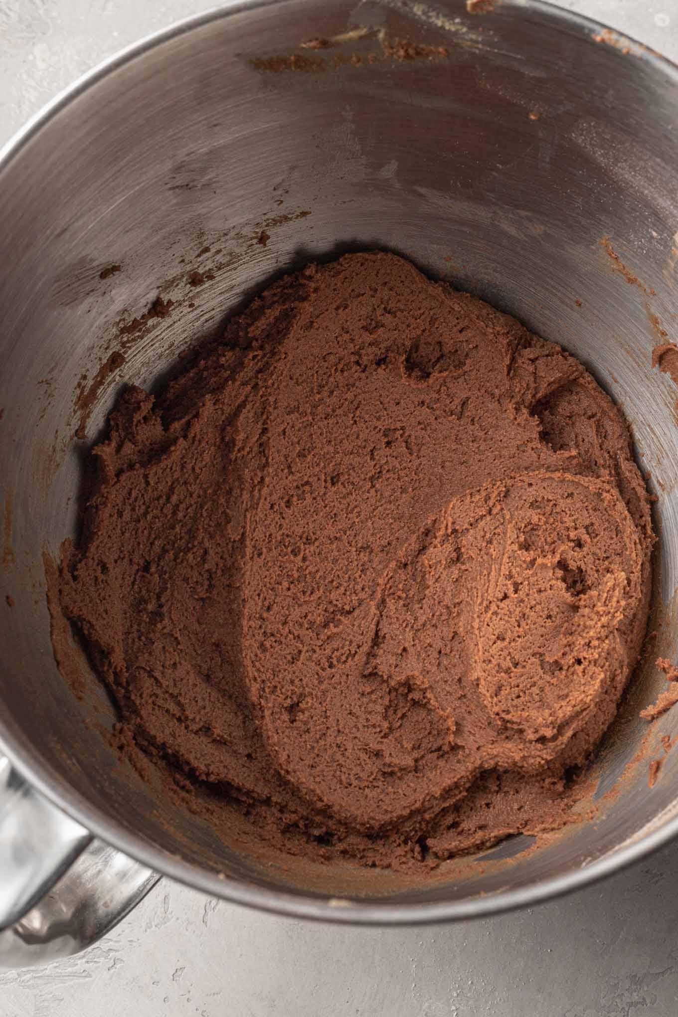 An overhead view of peanut butter chocolate cookie dough in the bowl of a stand mixer. 