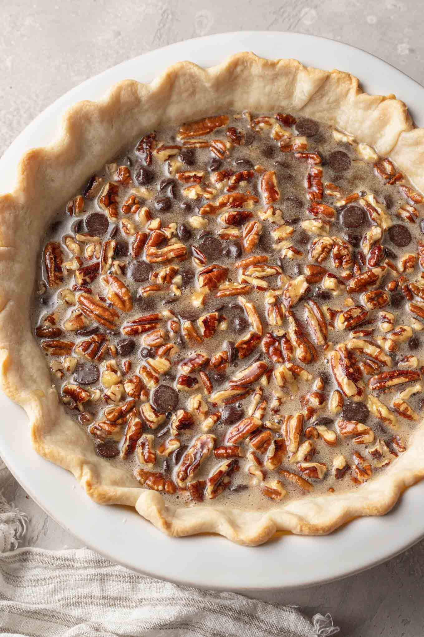 An overhead view of an unbaked pecan chocolate pie. 