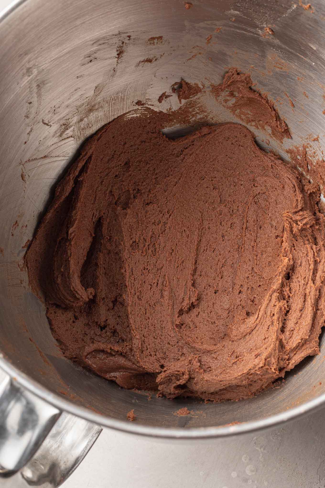 An overhead view of chocolate peppermint cookie dough in the bowl of a stand mixer. 