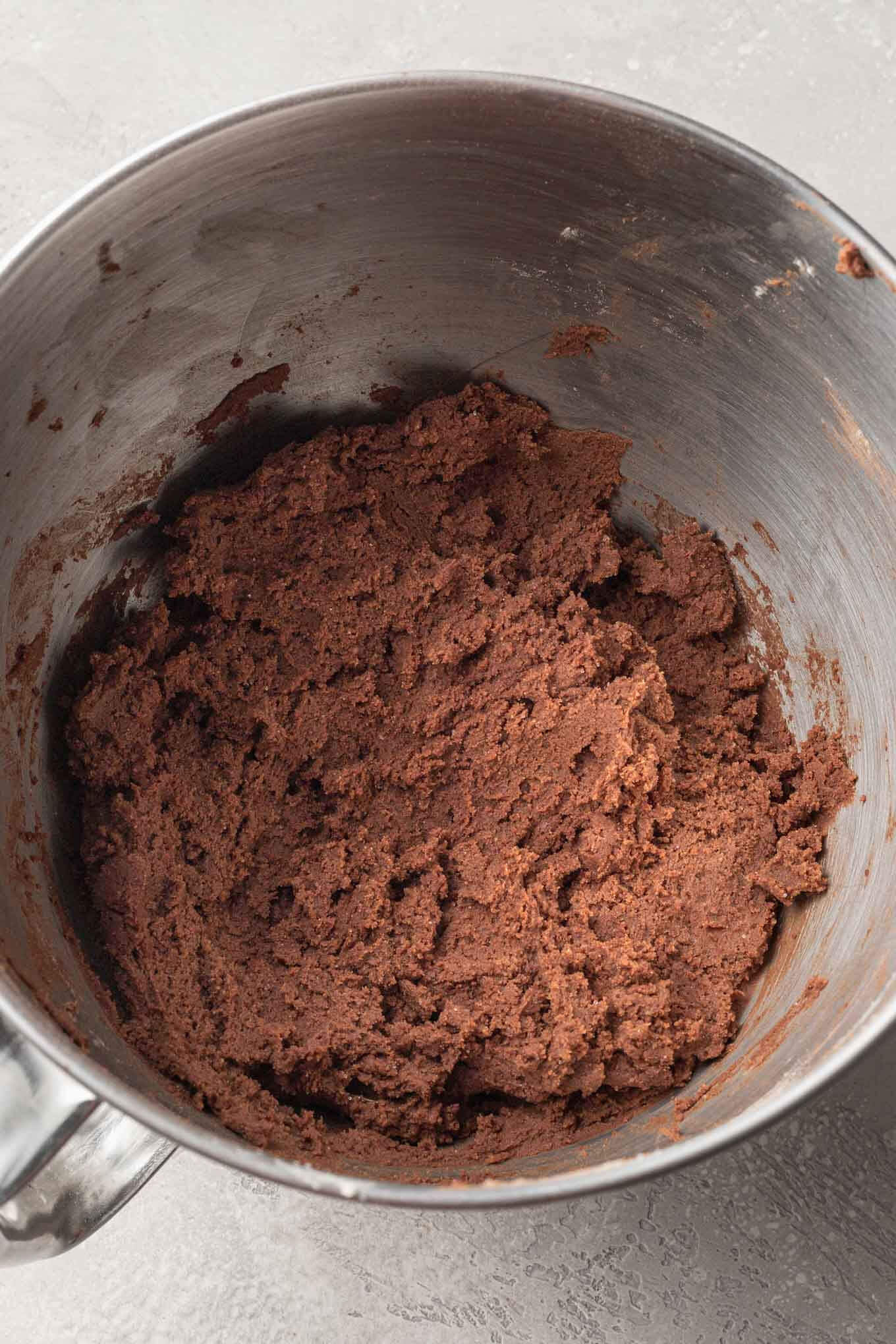 An overhead view of cocoa powder sugar cookie dough in a mixing bowl. 