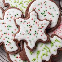 Several iced chocolate sugar cookies on a wire cooling rack.