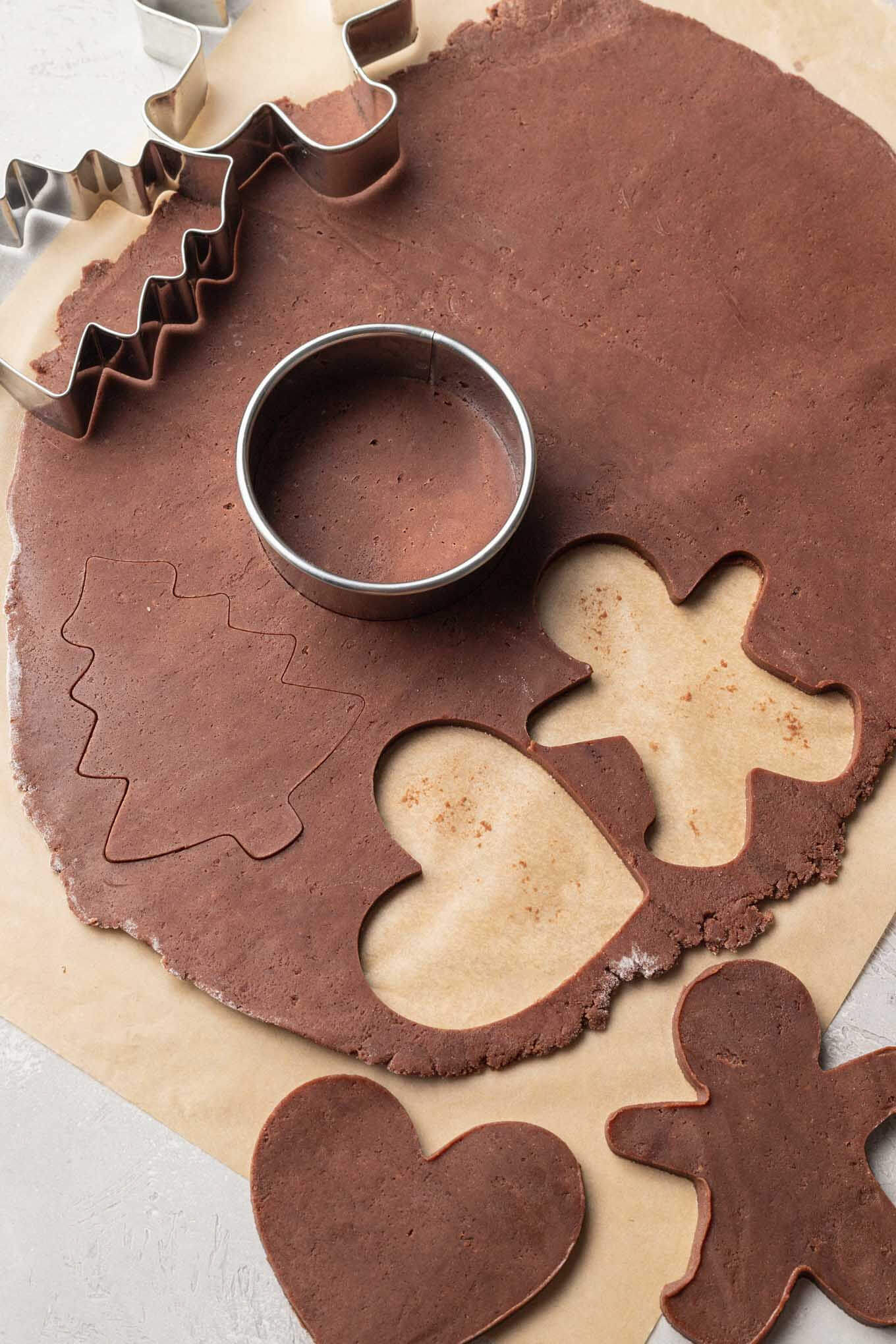 An overhead view of chocolate sugar cookie dough being cut into shapes. 