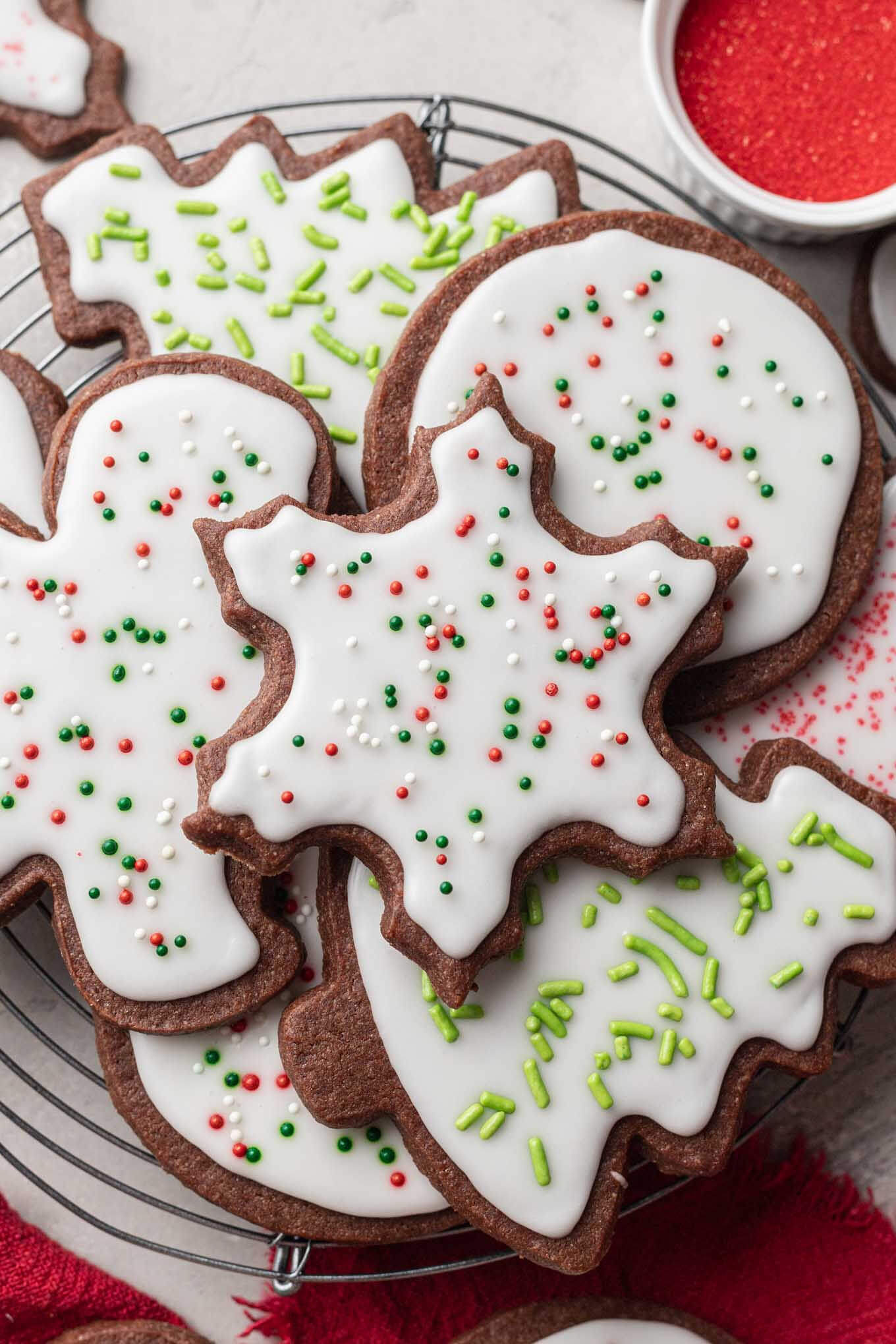 An overhead view of chocolate sugar cookies stacked on a wire cooling rack. 