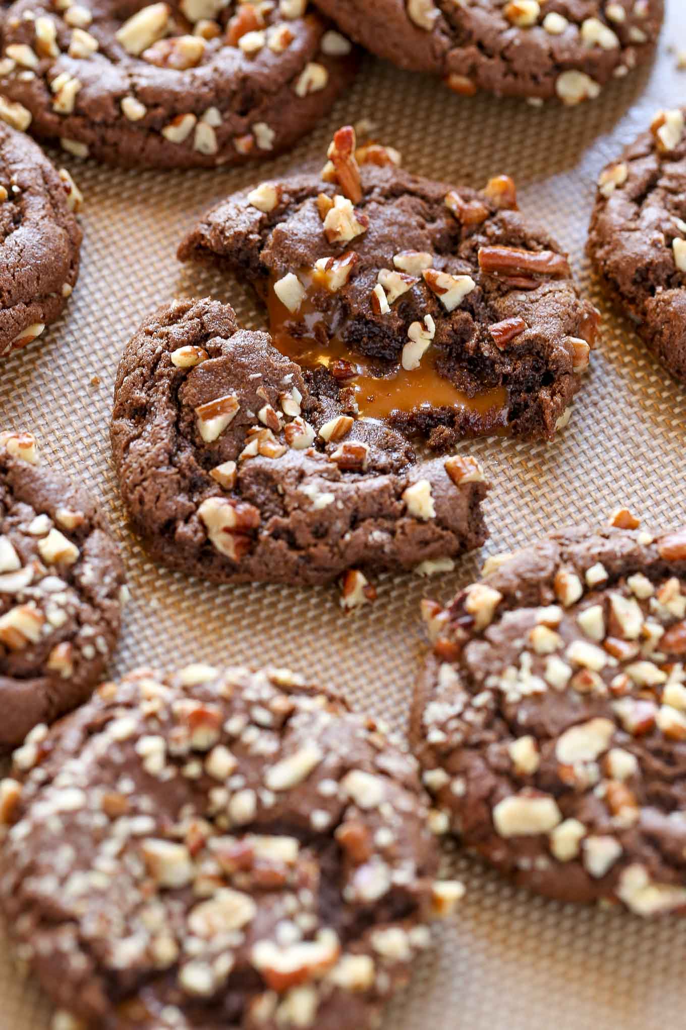 A close up view of chocolate turtle cookies on a baking sheet. 