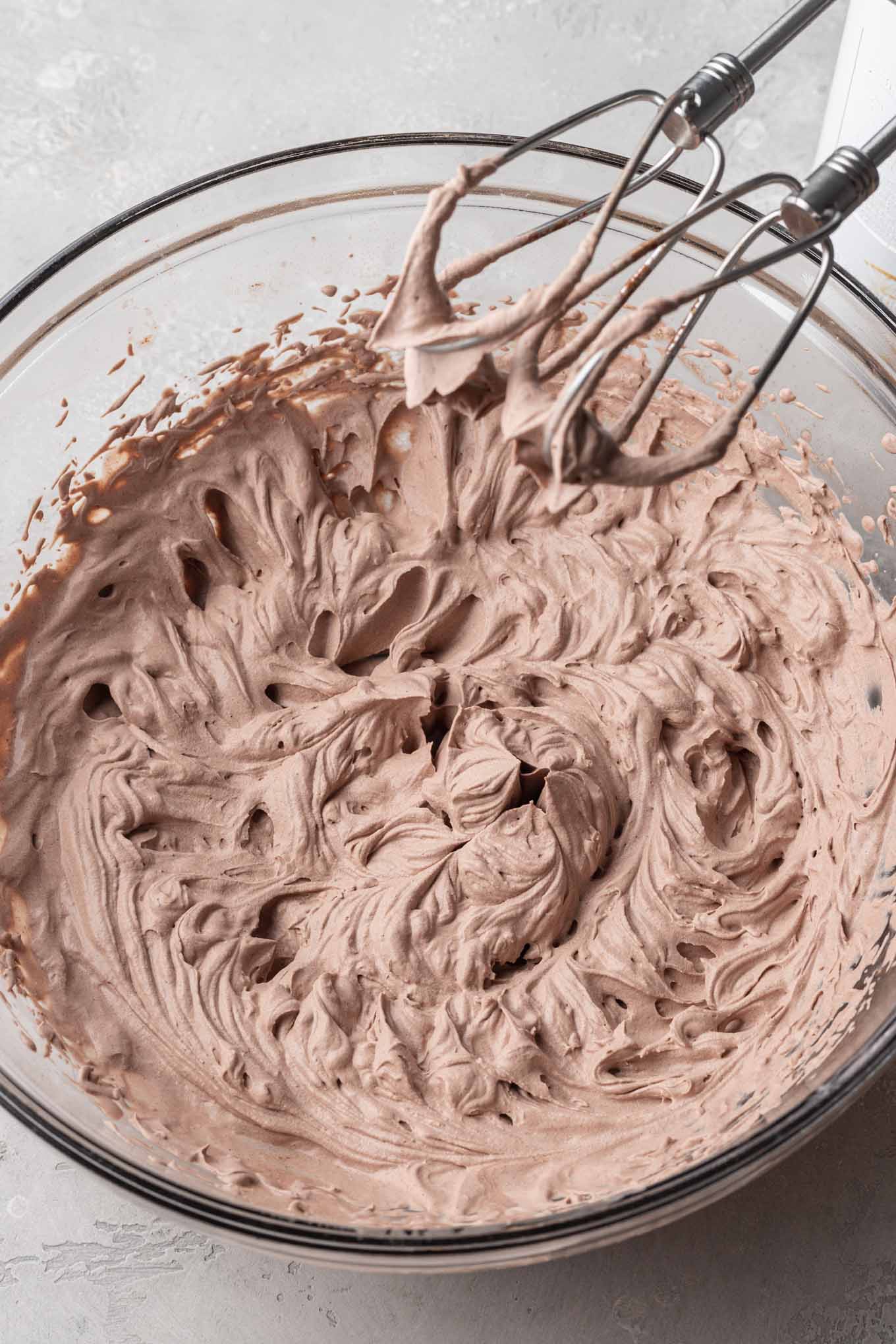 A glass mixing bowl filled with the finished chocolate whipped cream. 