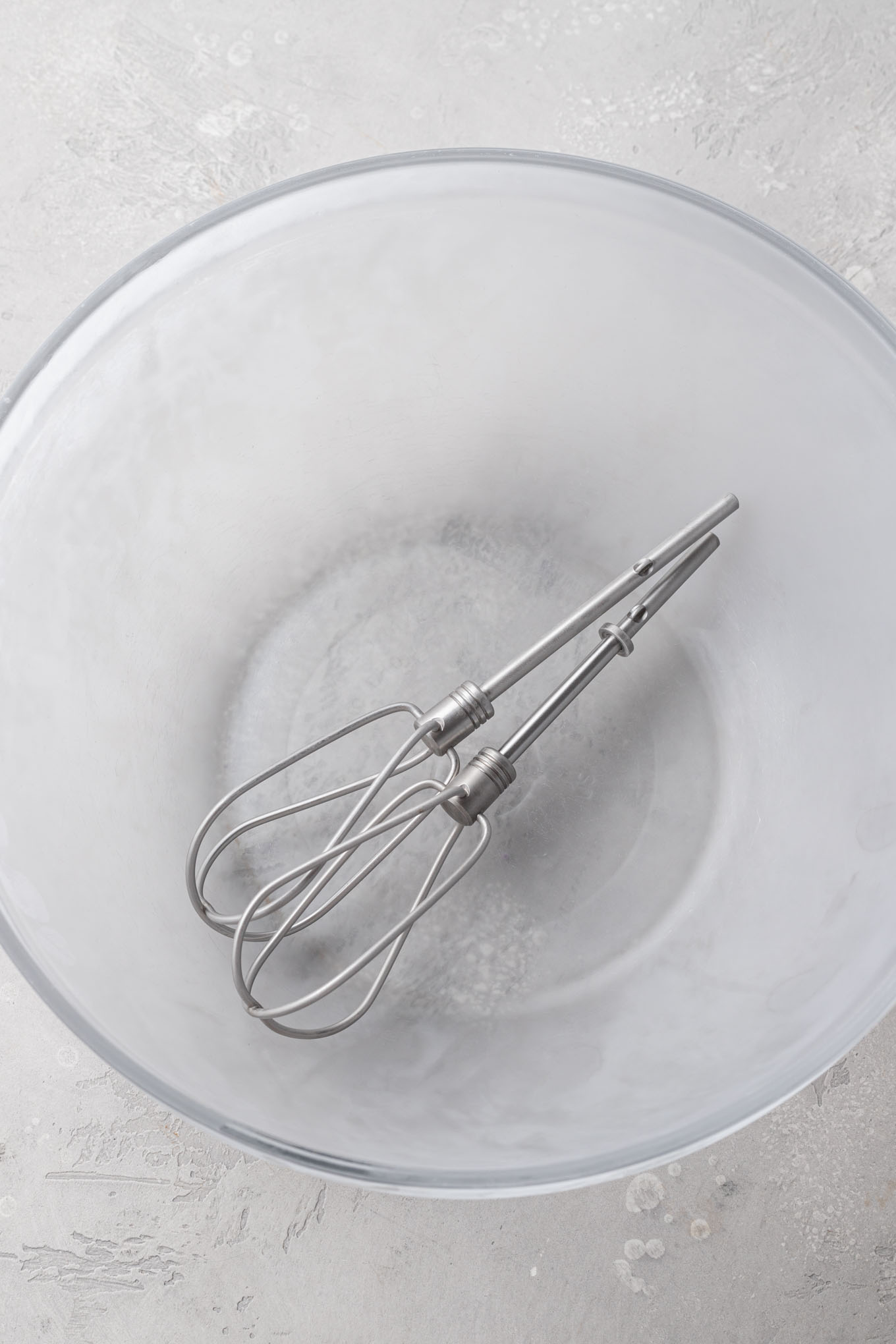 A chilled mixing bowl with the beaters resting inside of it.