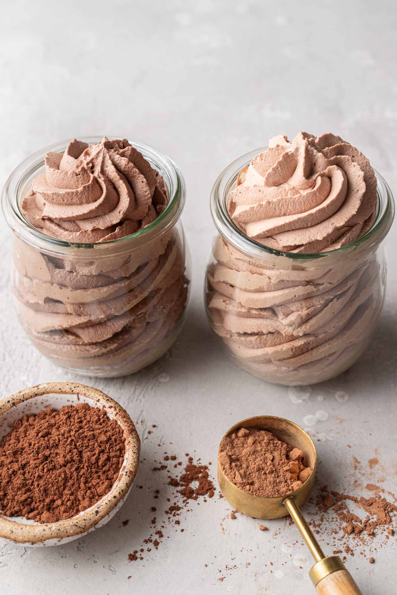 Two small jars filled with chocolate whipped cream. The jar on the left is made with Dutch process cocoa powder and the jar on the right is made with natural cocoa powder.