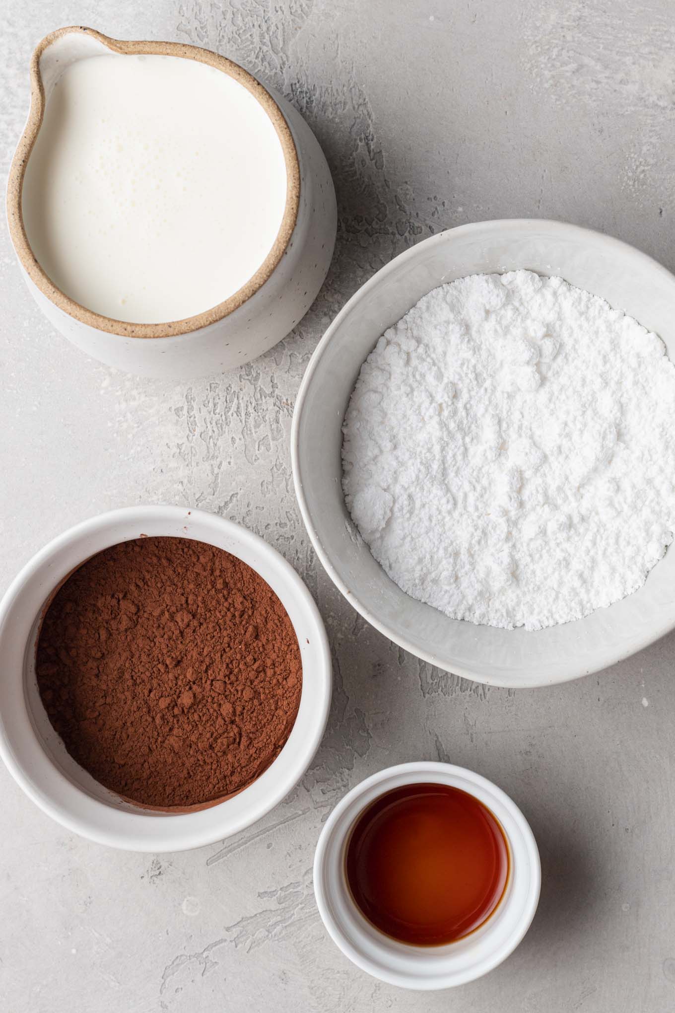 An overhead view of the ingredients needed to make chocolate whipped cream in various bowls and cups.