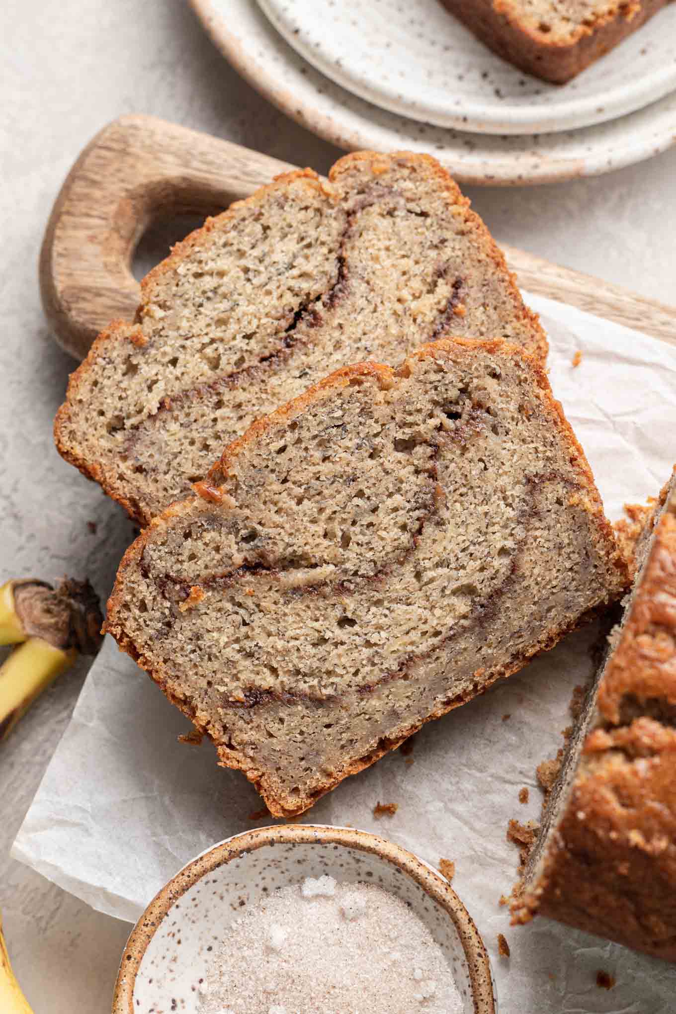 An overhead view of two slices of cinnamon swirl banana bread on a cutting board. 