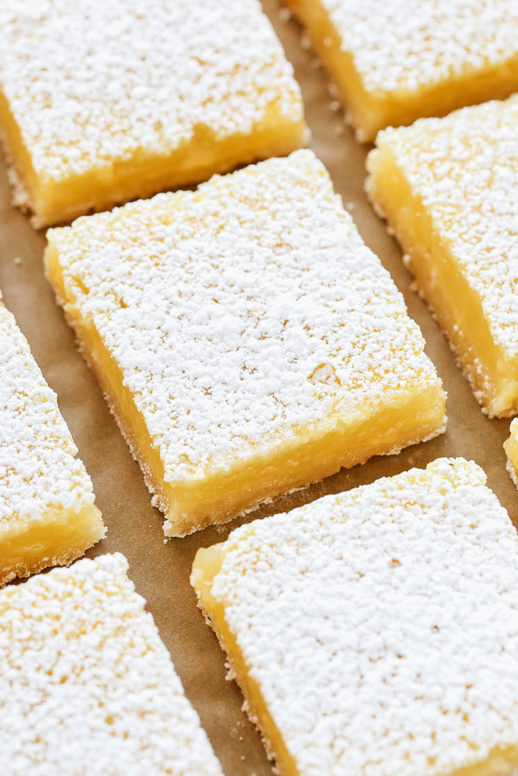 Sliced lemon bars on a piece of brown parchment paper.